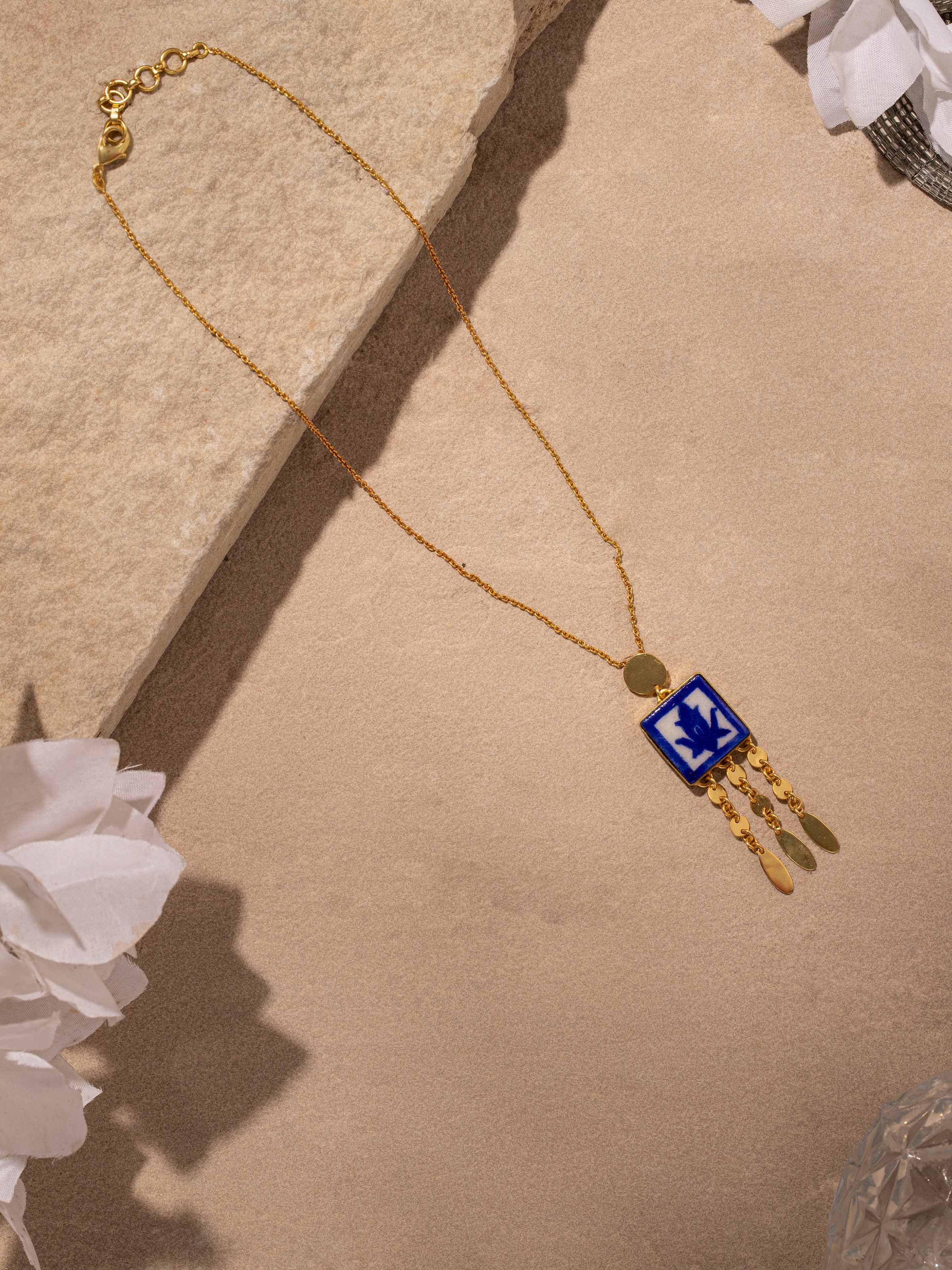 Side view of blue pottery pendant & chain emphasizing its unique shape and design.