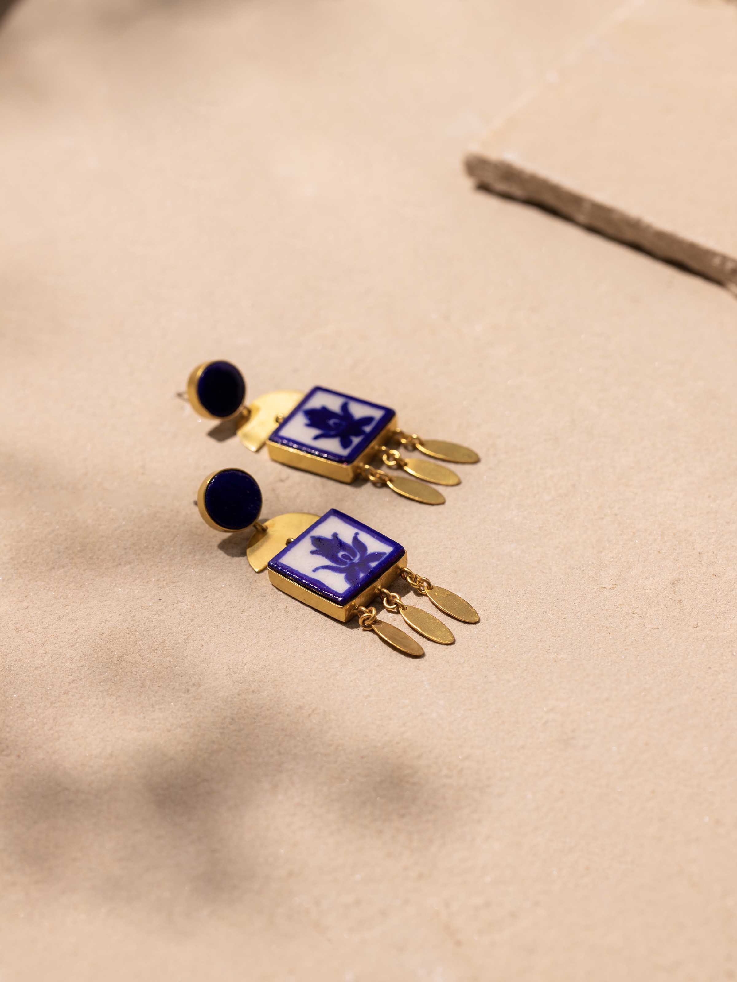 Detailed close-up of blue pottery drop earrings focusing on design and texture