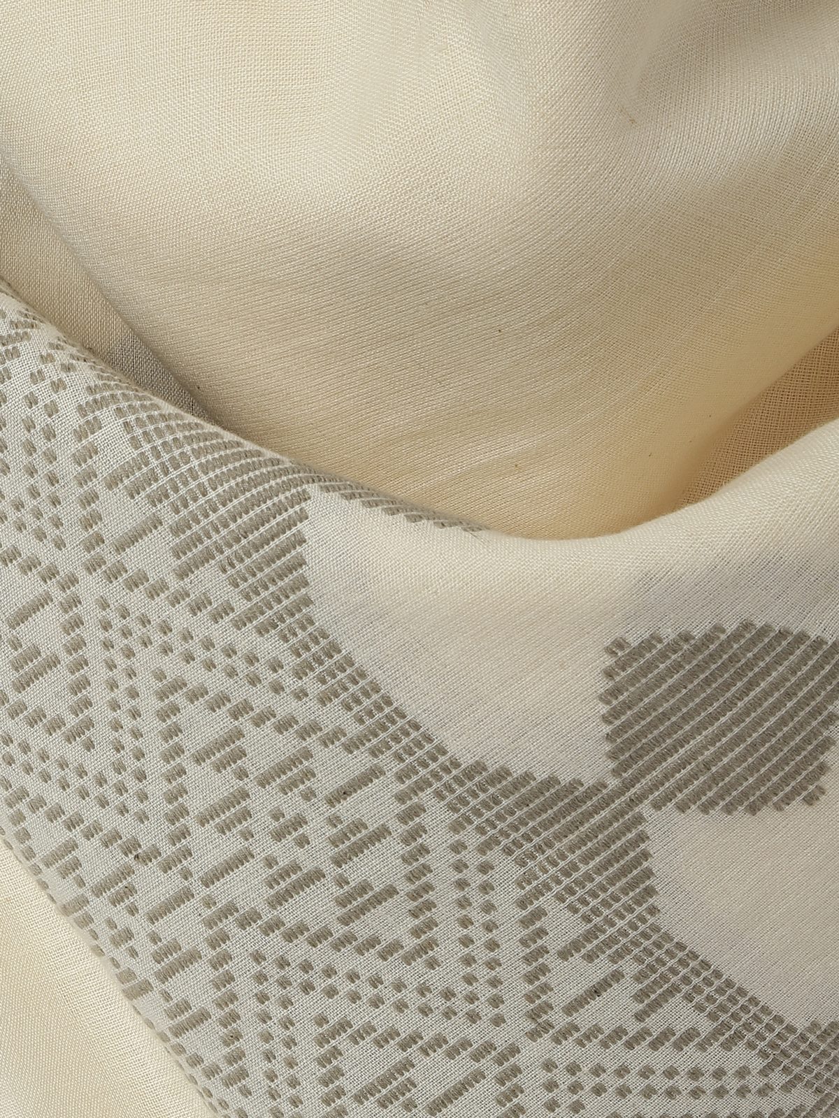 Close-up of extra-weft pattern on white cotton stole showcasing handloom texture.