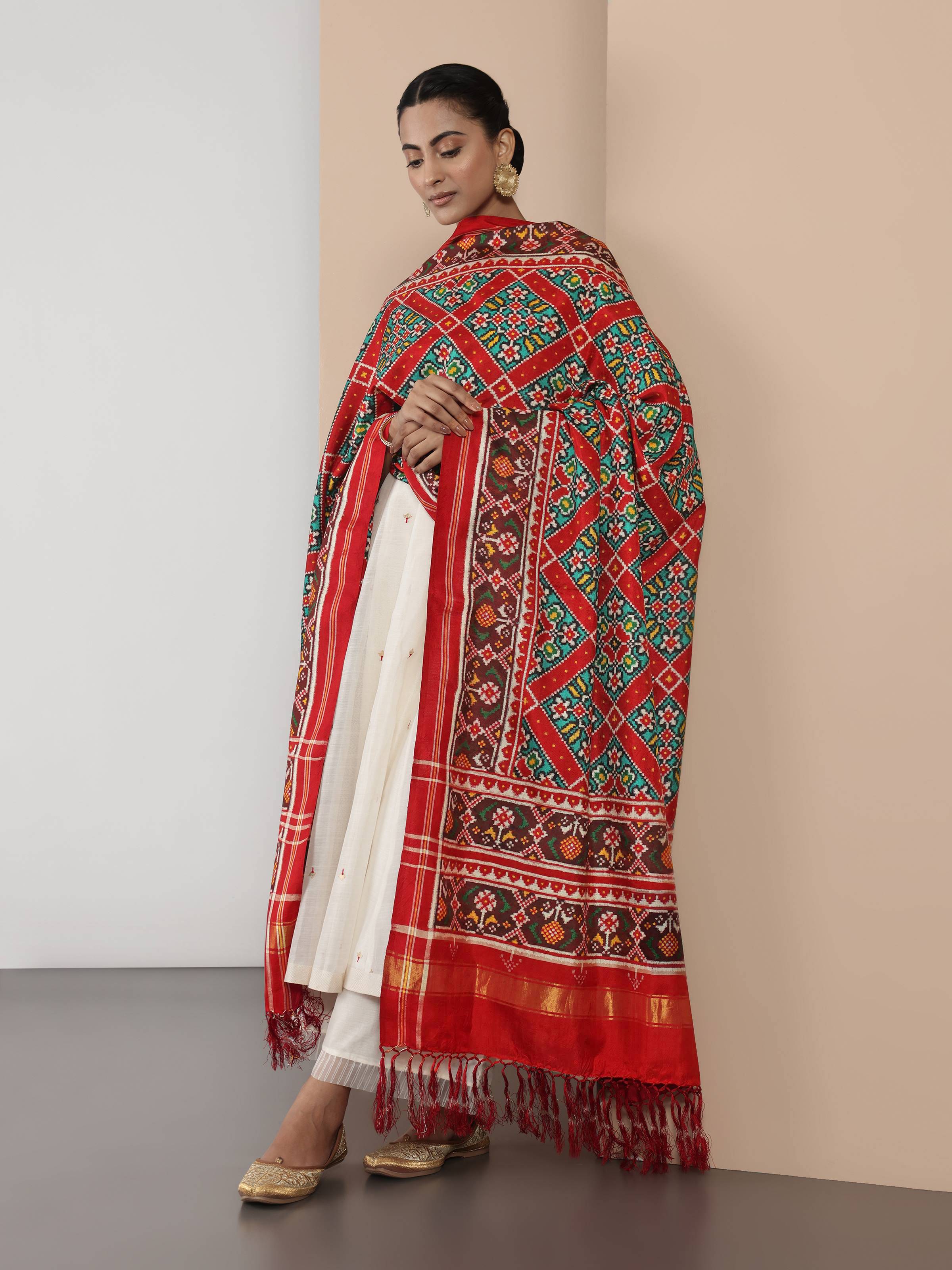 Lifestyle image of red silk Patola dupatta styled with contrast ethnic wear