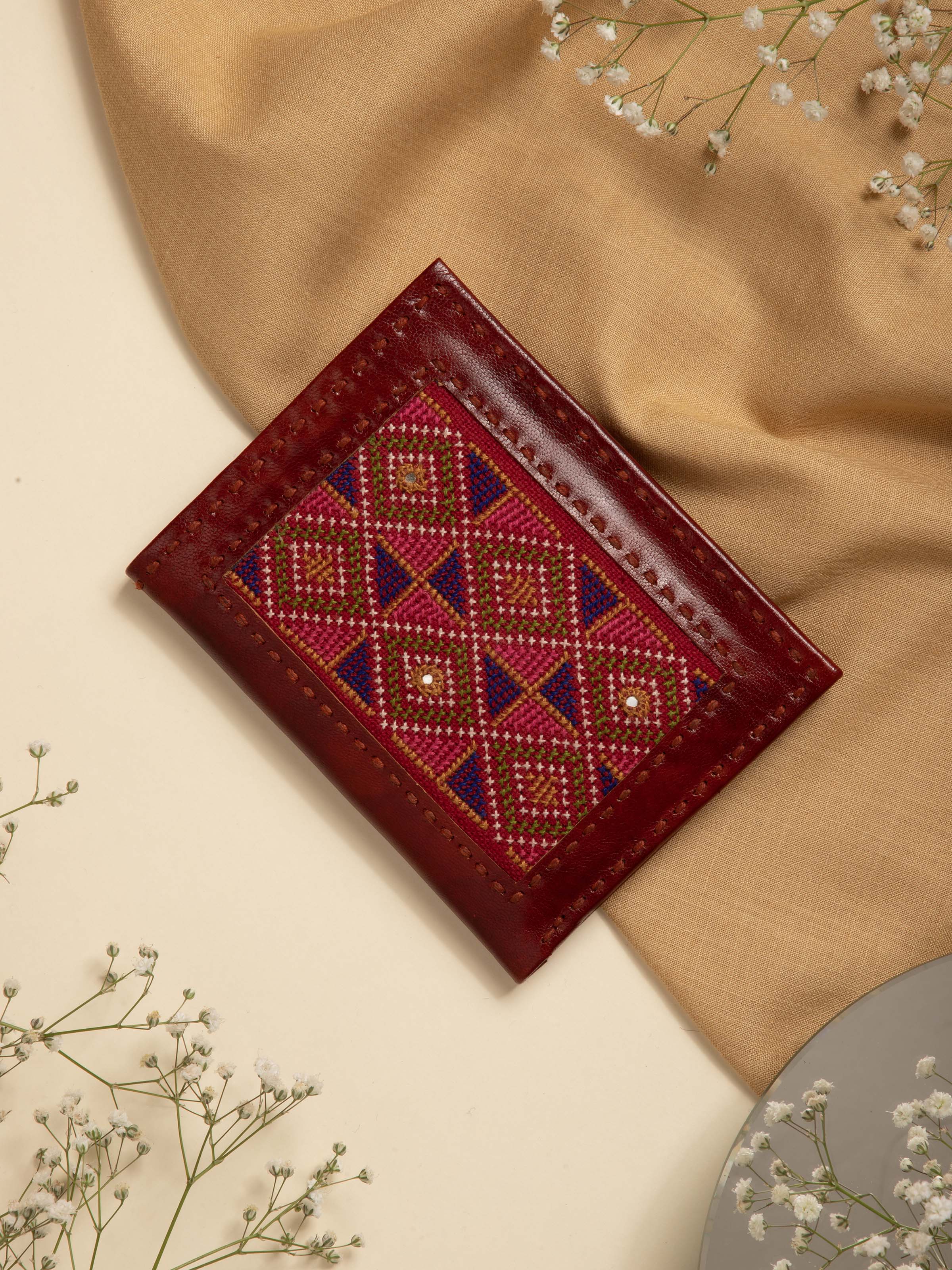 Side view of tan Kutchi leather embroidered wallet highlighting detailed stitching and design elements