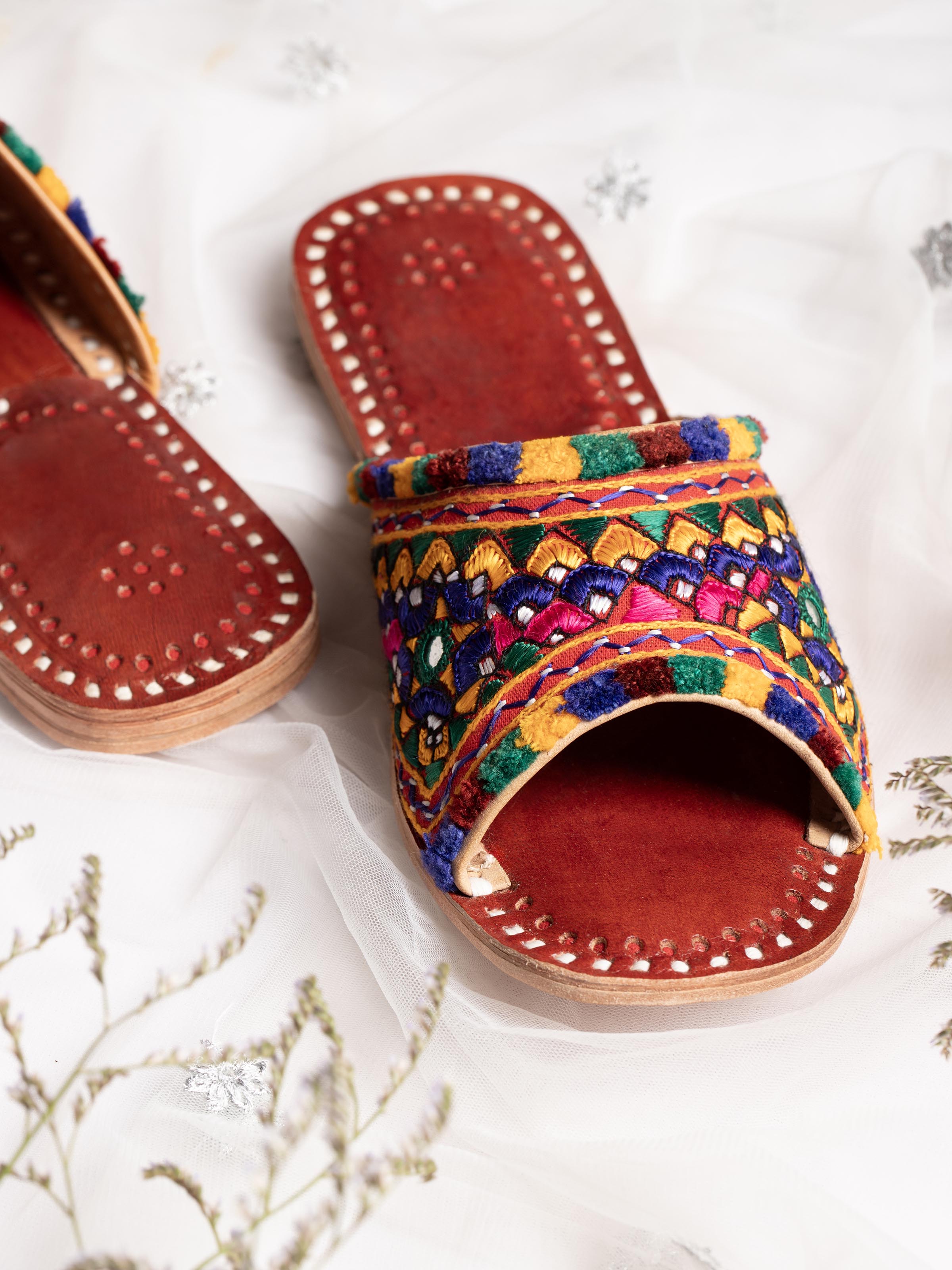 Close-up of tan leather kutch embroidered slides highlighting the fine embroidery details