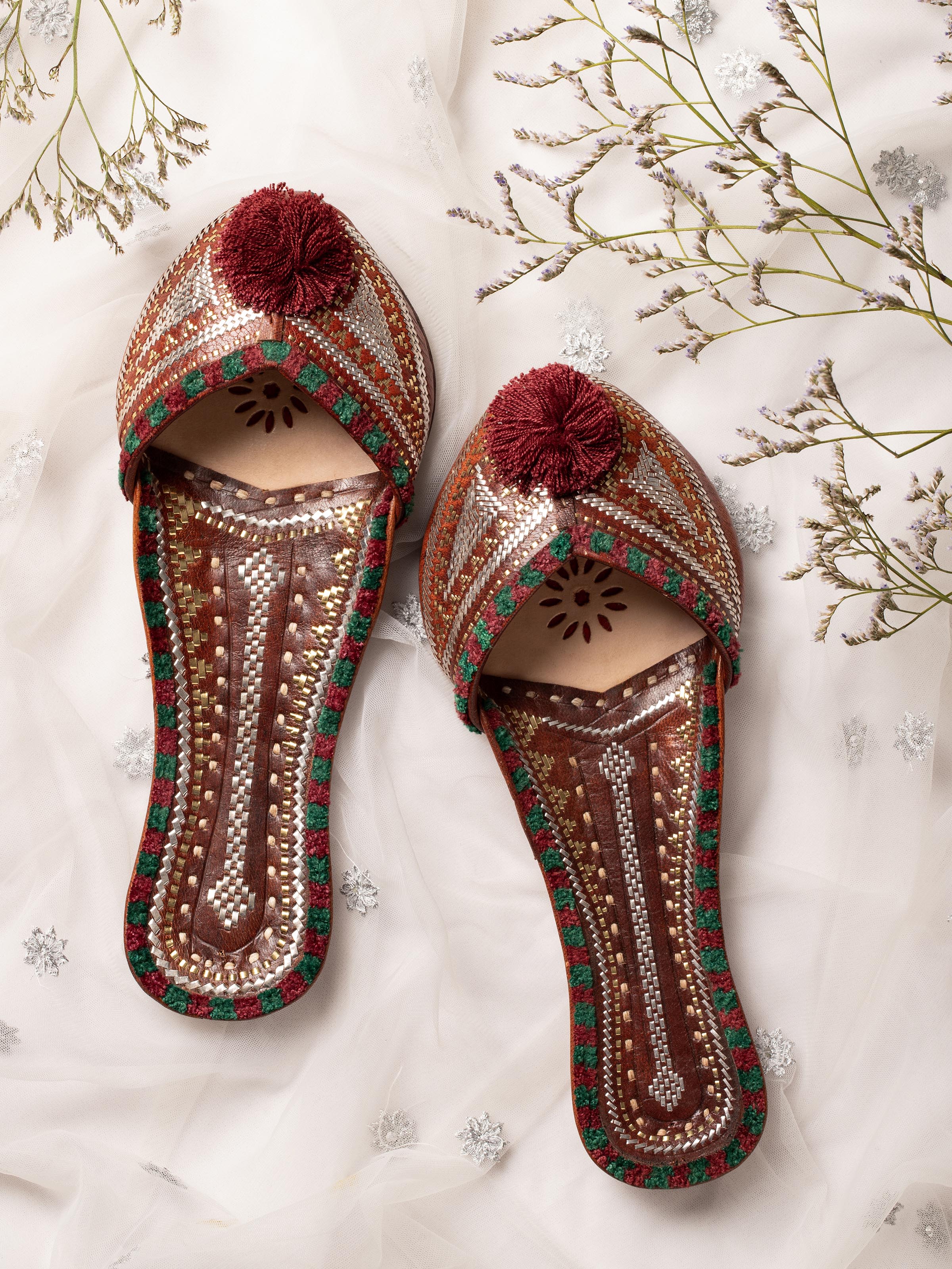 Side view of tan leather Kutch juttis highlighting embroidery and craftsmanship