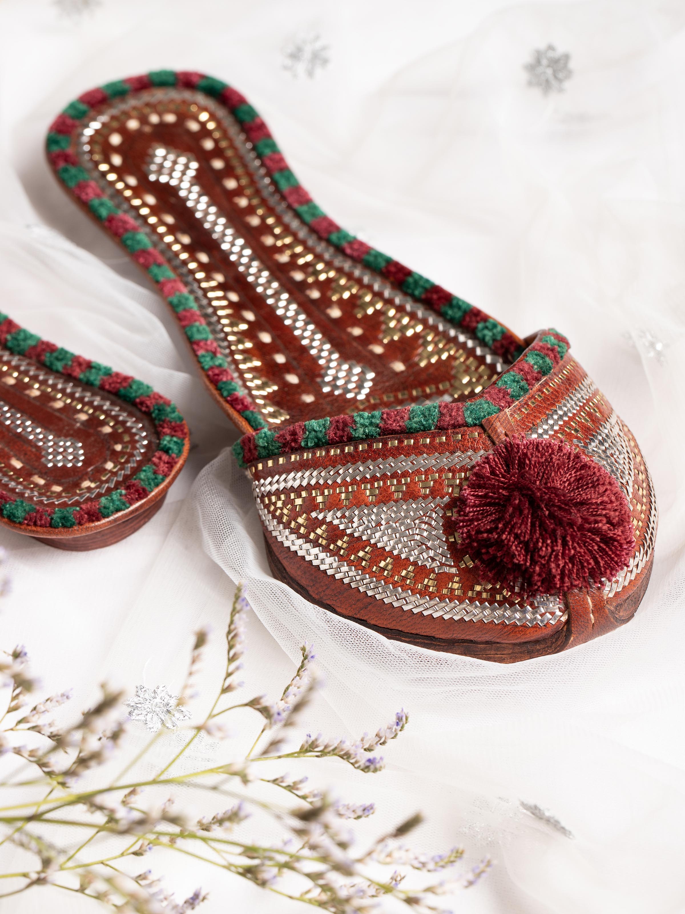 Close-up of tan leather Kutch juttis focusing on embroidery details and leather texture