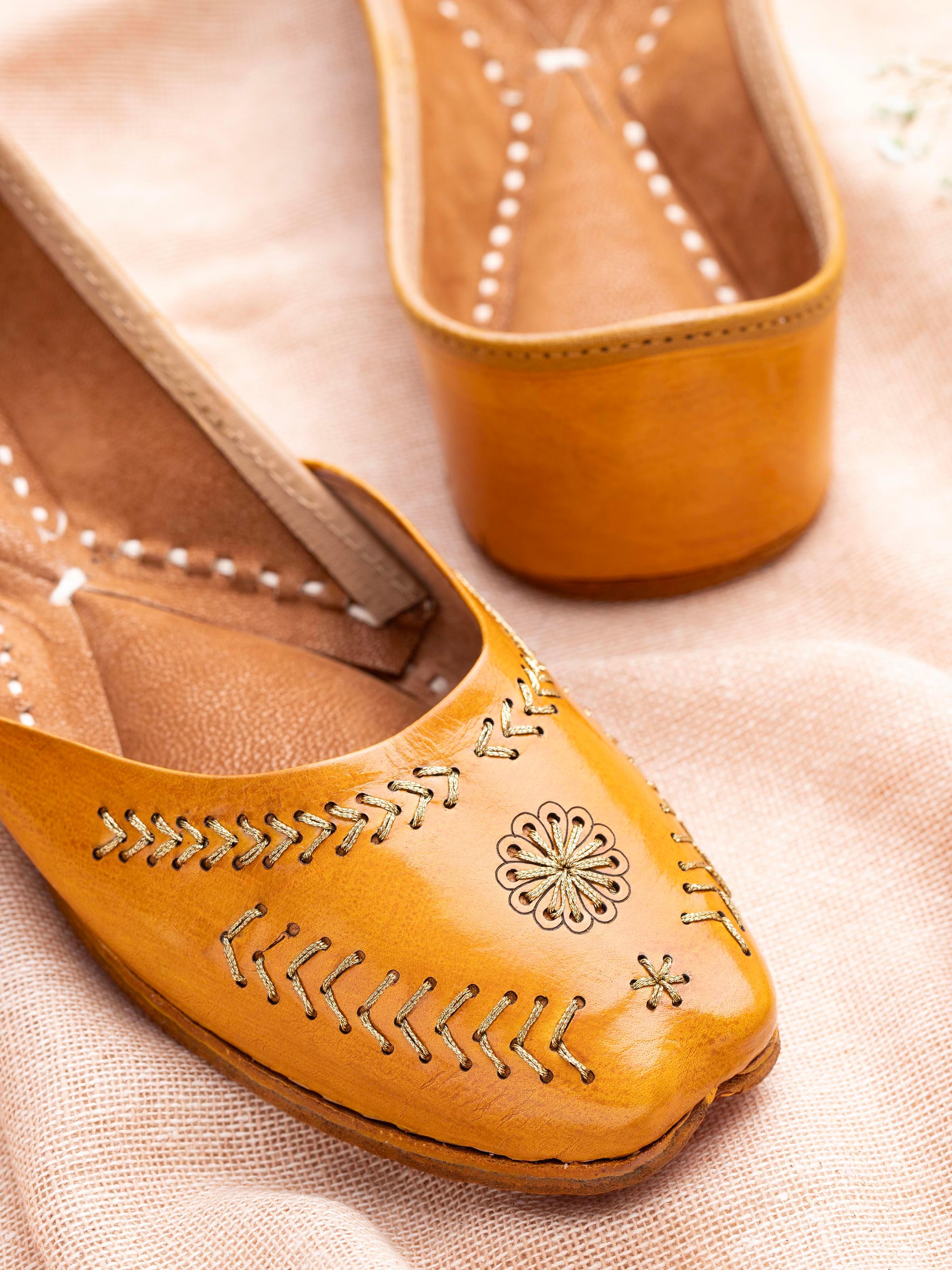 Close-up of mustard leather Haryana juttis focusing on embroidery details and leather quality