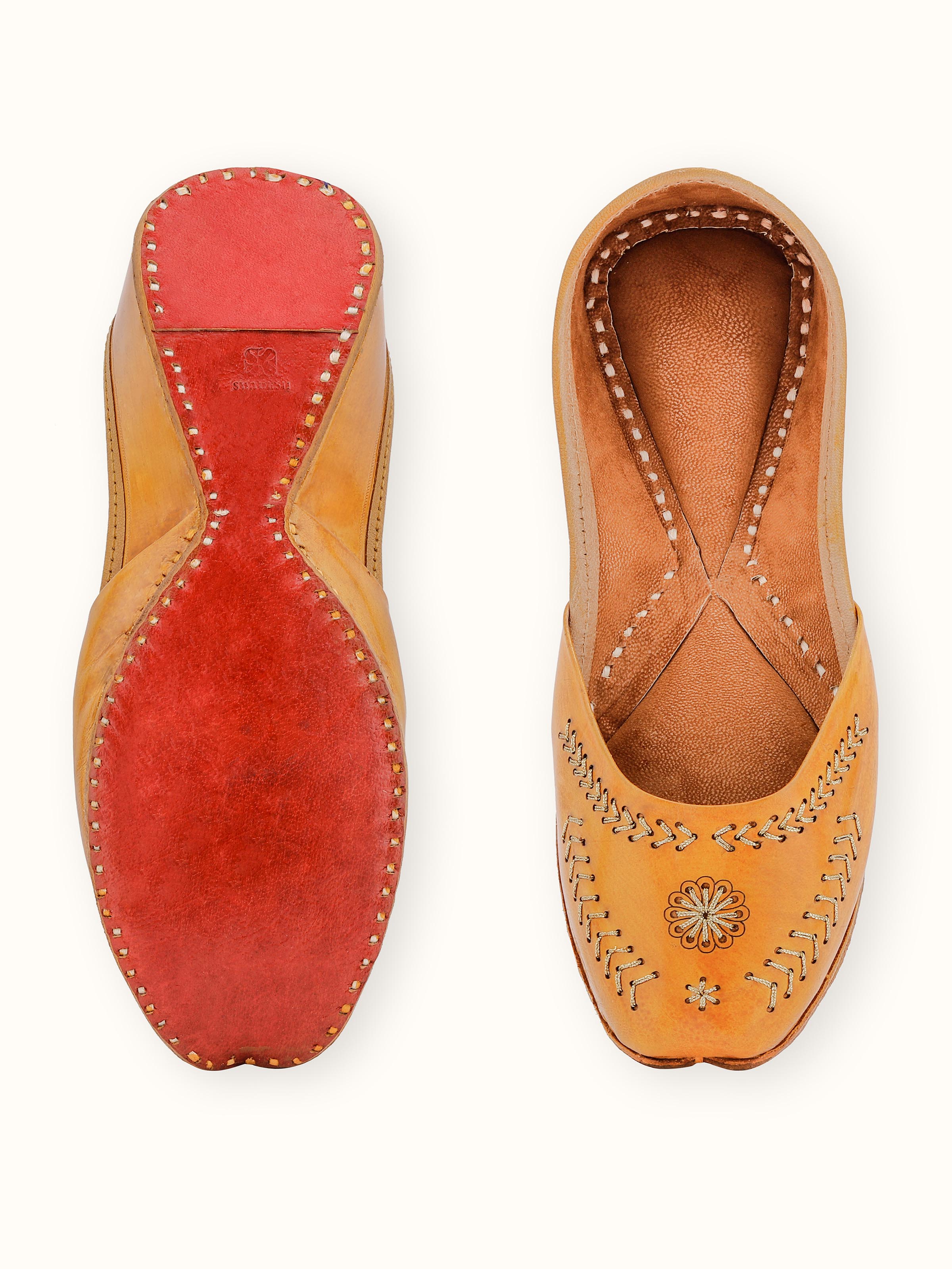 Detailed view of mustard leather Haryana juttis emphasizing the fine embroidery and leatherwork