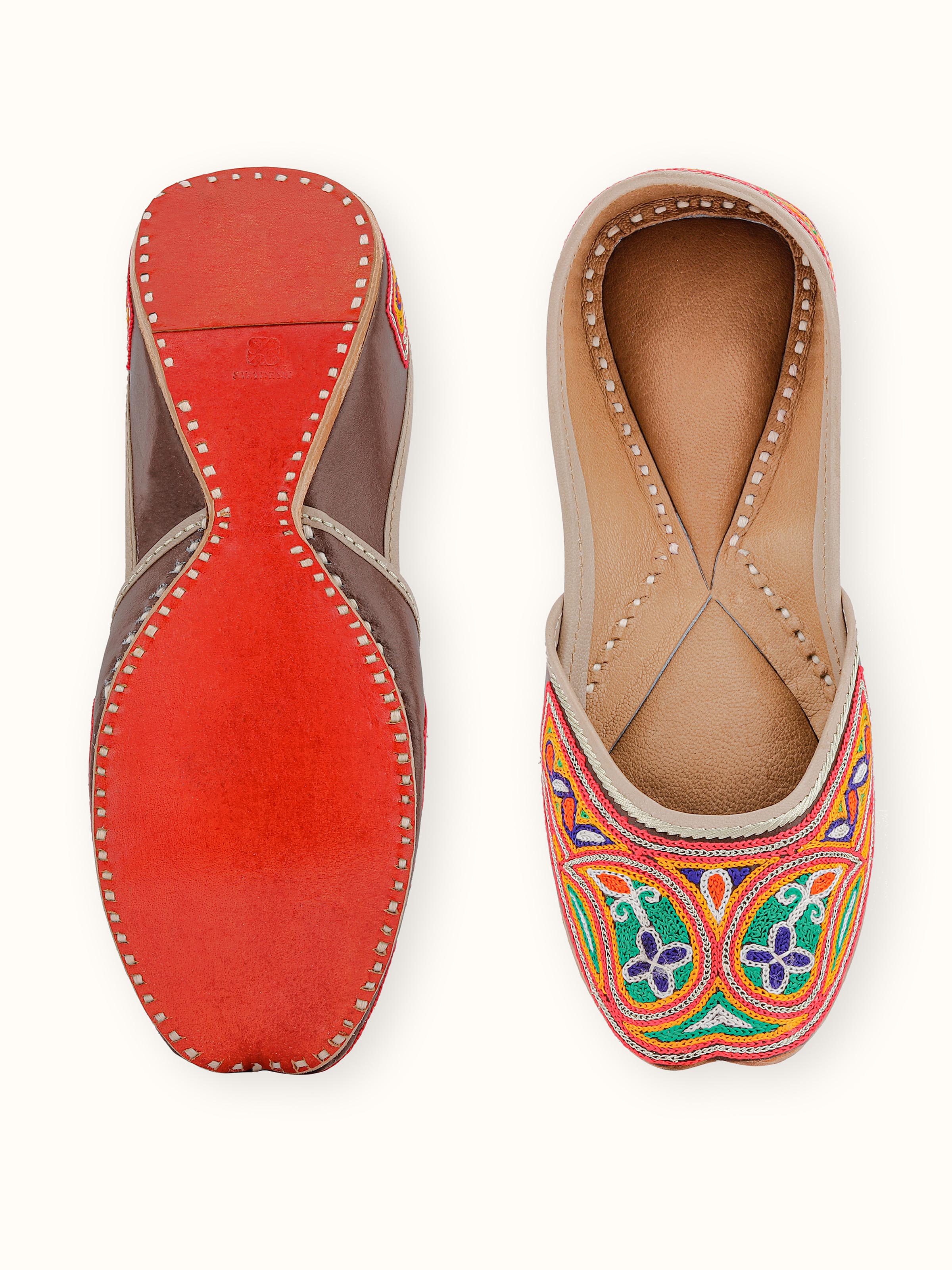 Close-up view of Tan leather haryana embroidered juttis emphasizing embroidery
