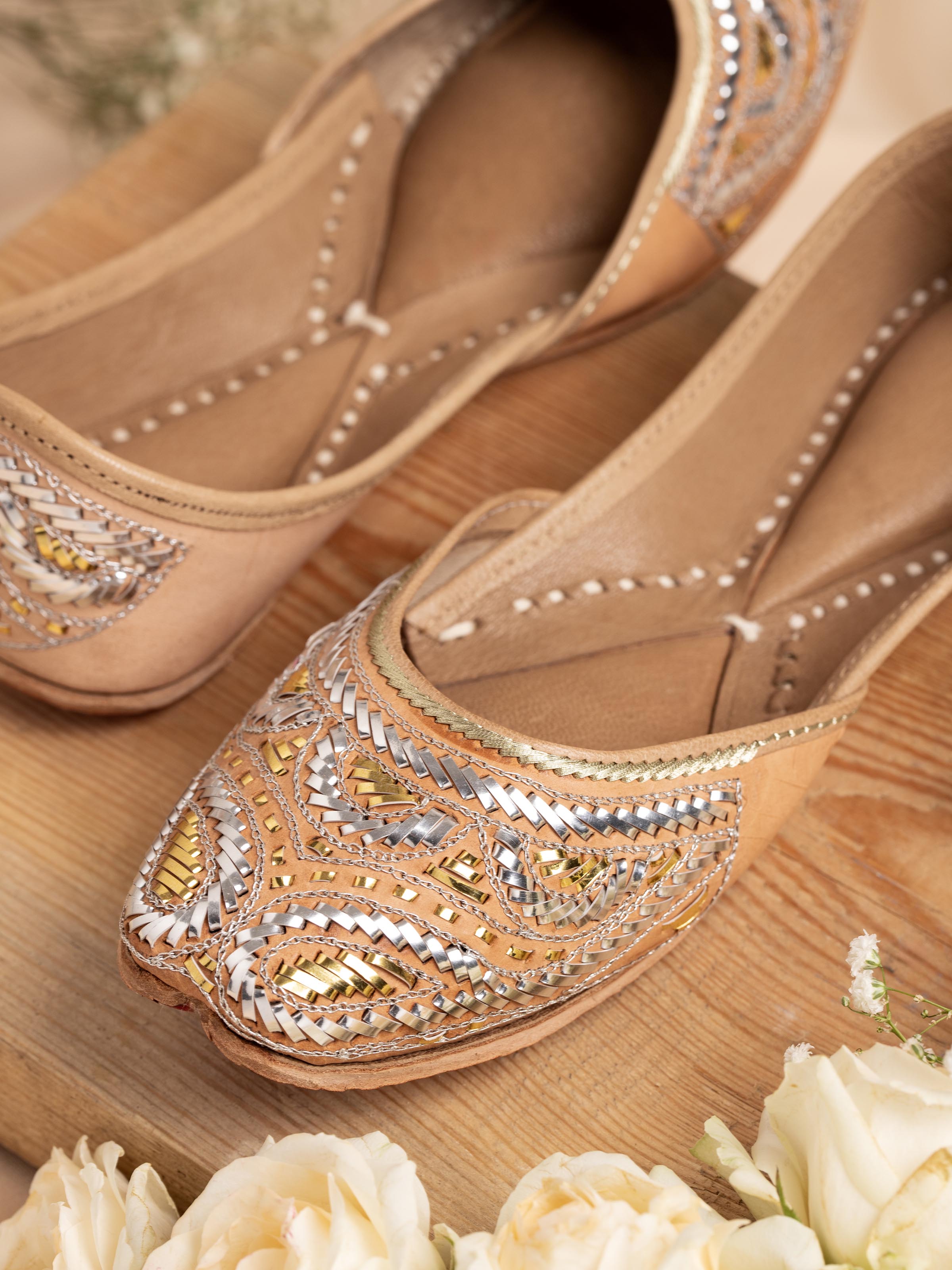 Close-up of Ecru Leather Haryana Juttis showing intricate embroidery and leather texture.