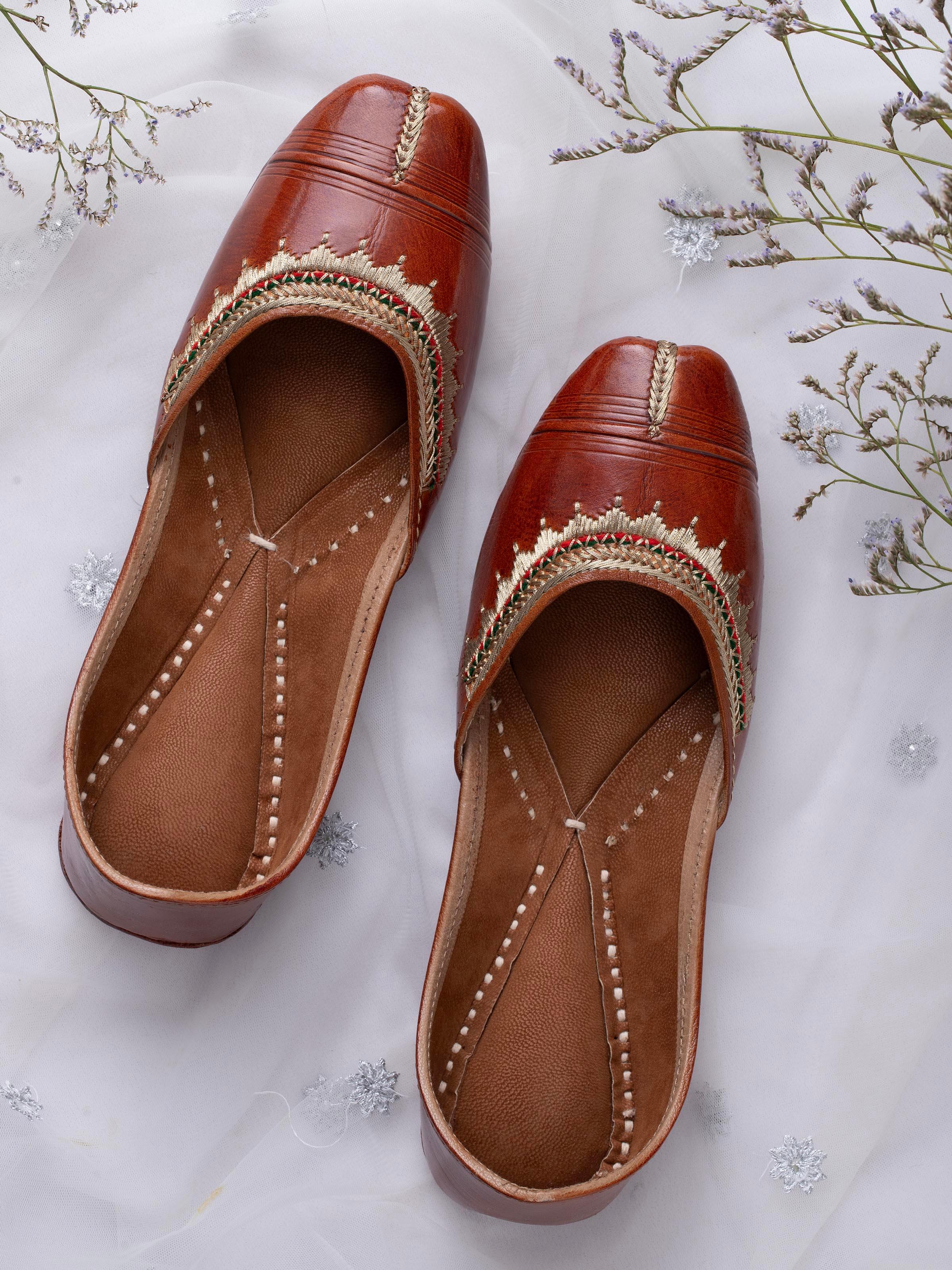 Side view of tan leather haryana juttis highlighting the detailed leatherwork