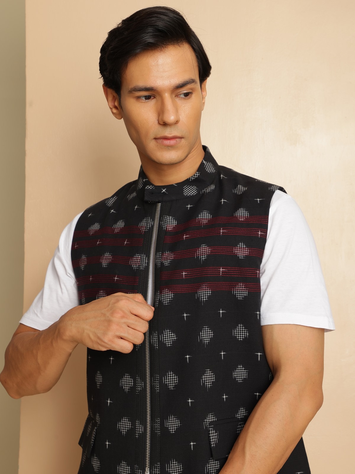 Model seated in traditional setting wearing the black Ikat jacket with ethnic ensemble.