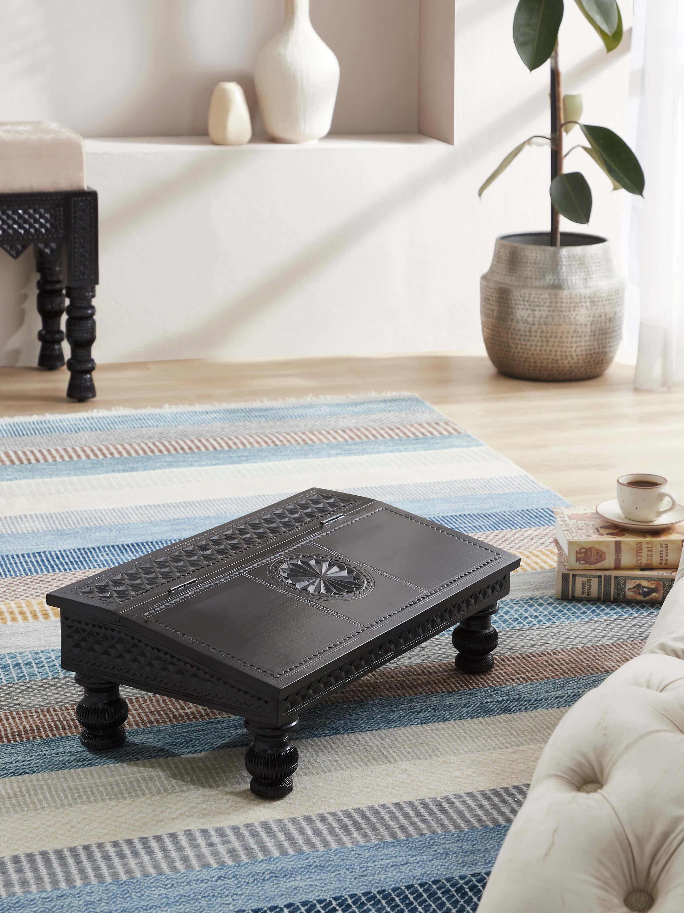 Side view of the carved teak wood portable table, showing its detailed craftsmanship and functionality.