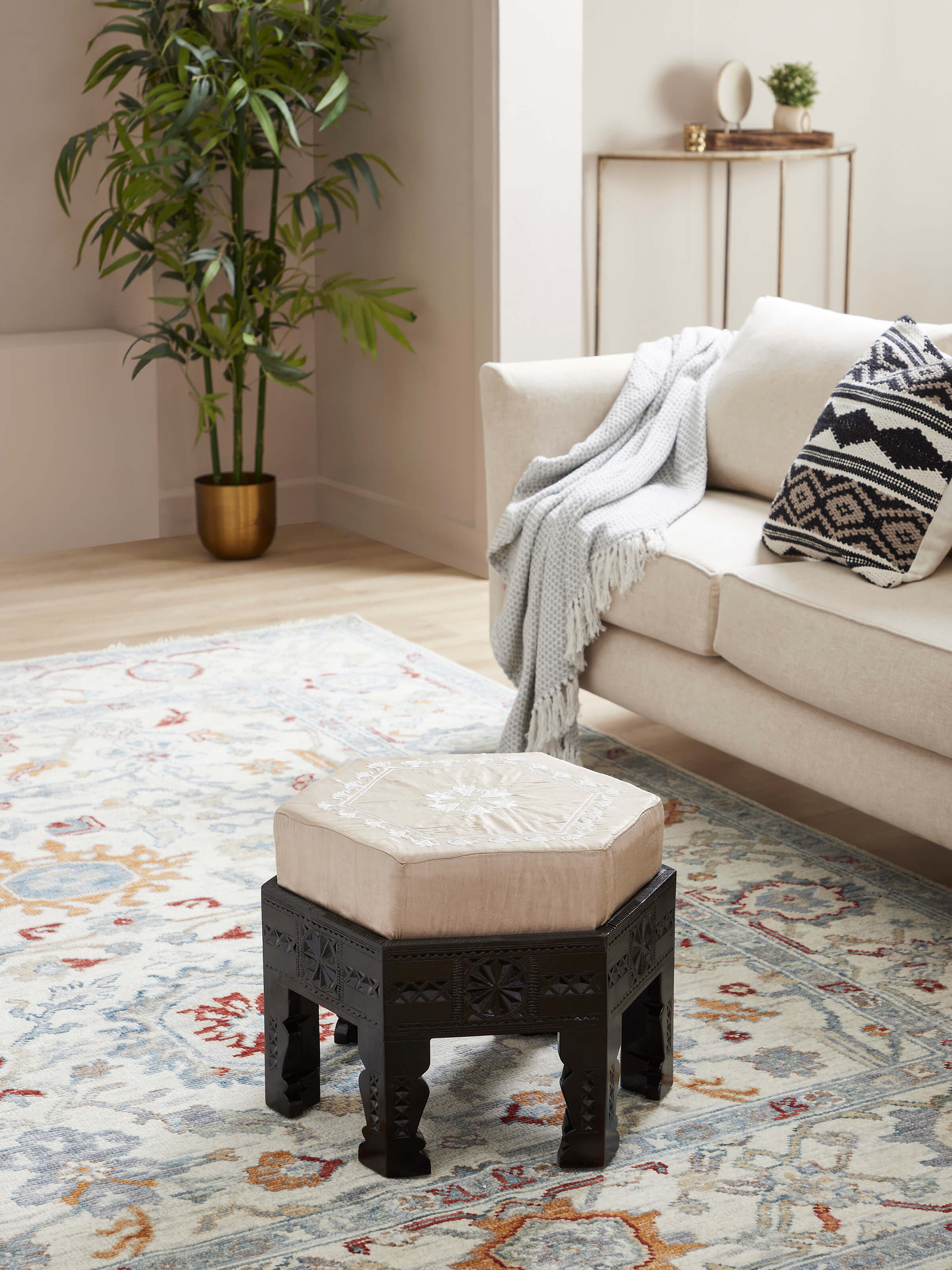 Side view of upholstered carved teak wood round pouffe highlighting elegant craftsmanship