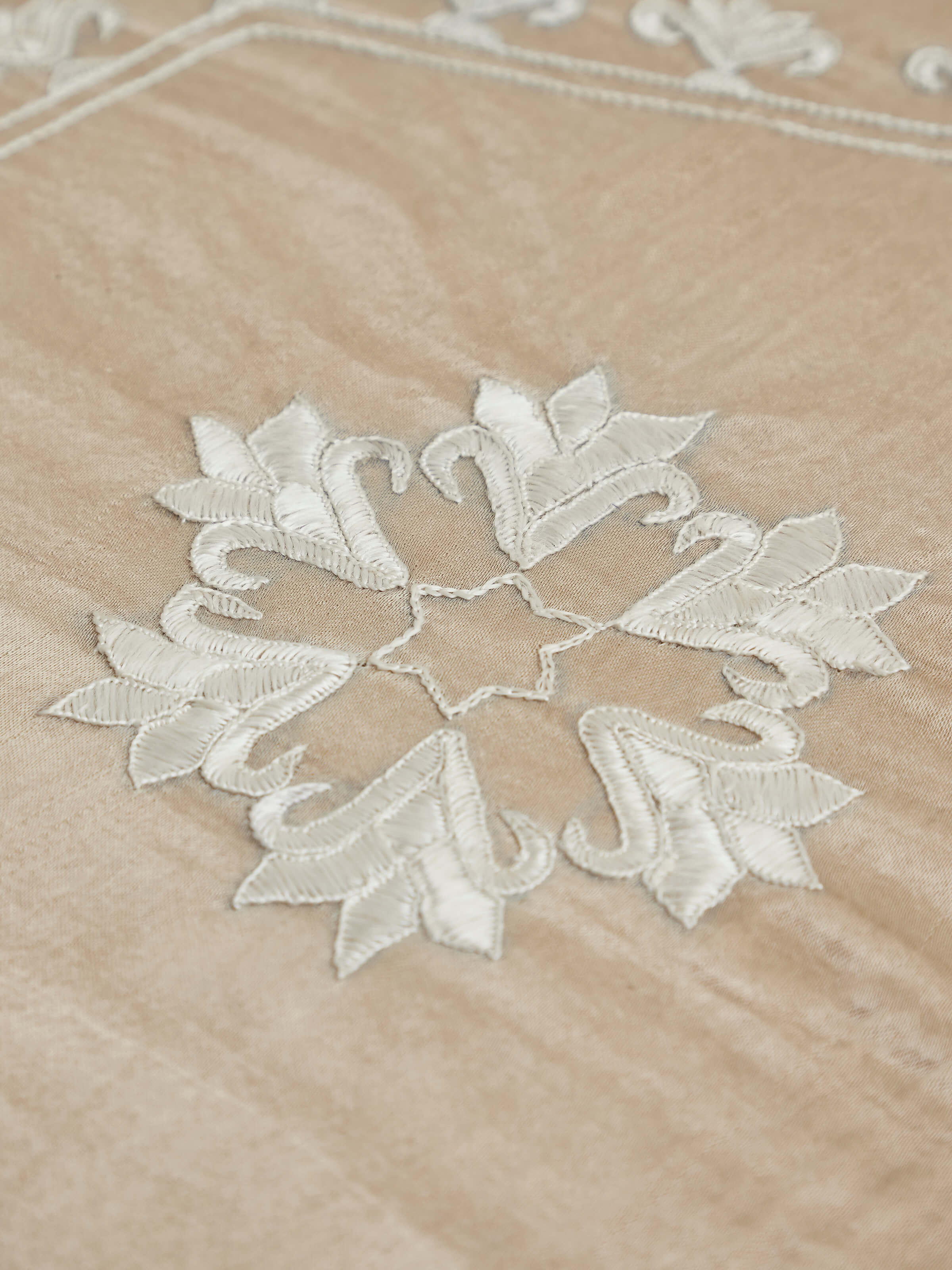 Close-up view of upholstered carved teak wood round pouffe highlighting intricate design details
