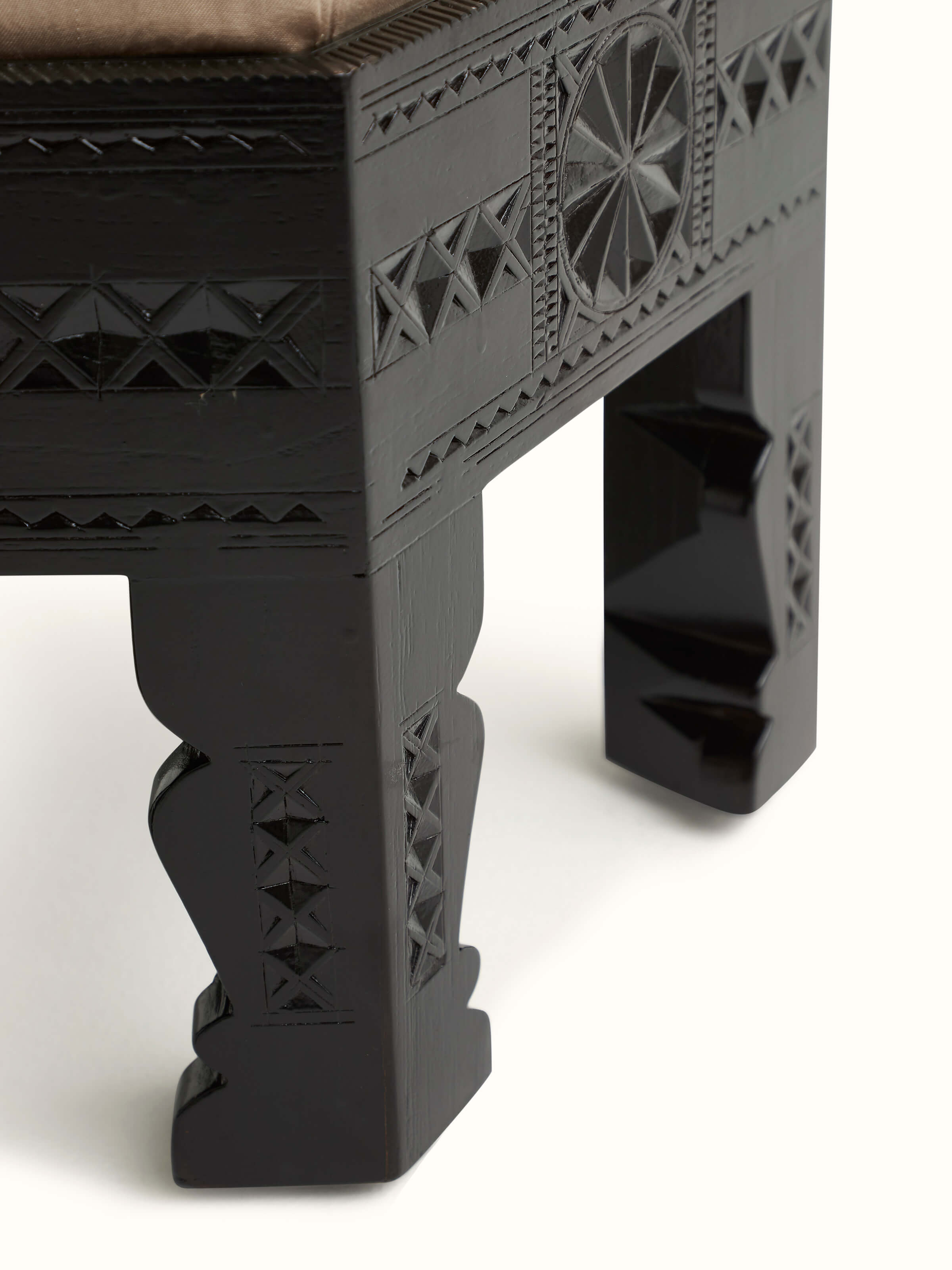 Bottom view of upholstered carved teak wood round pouffe displaying craftsmanship and support structure