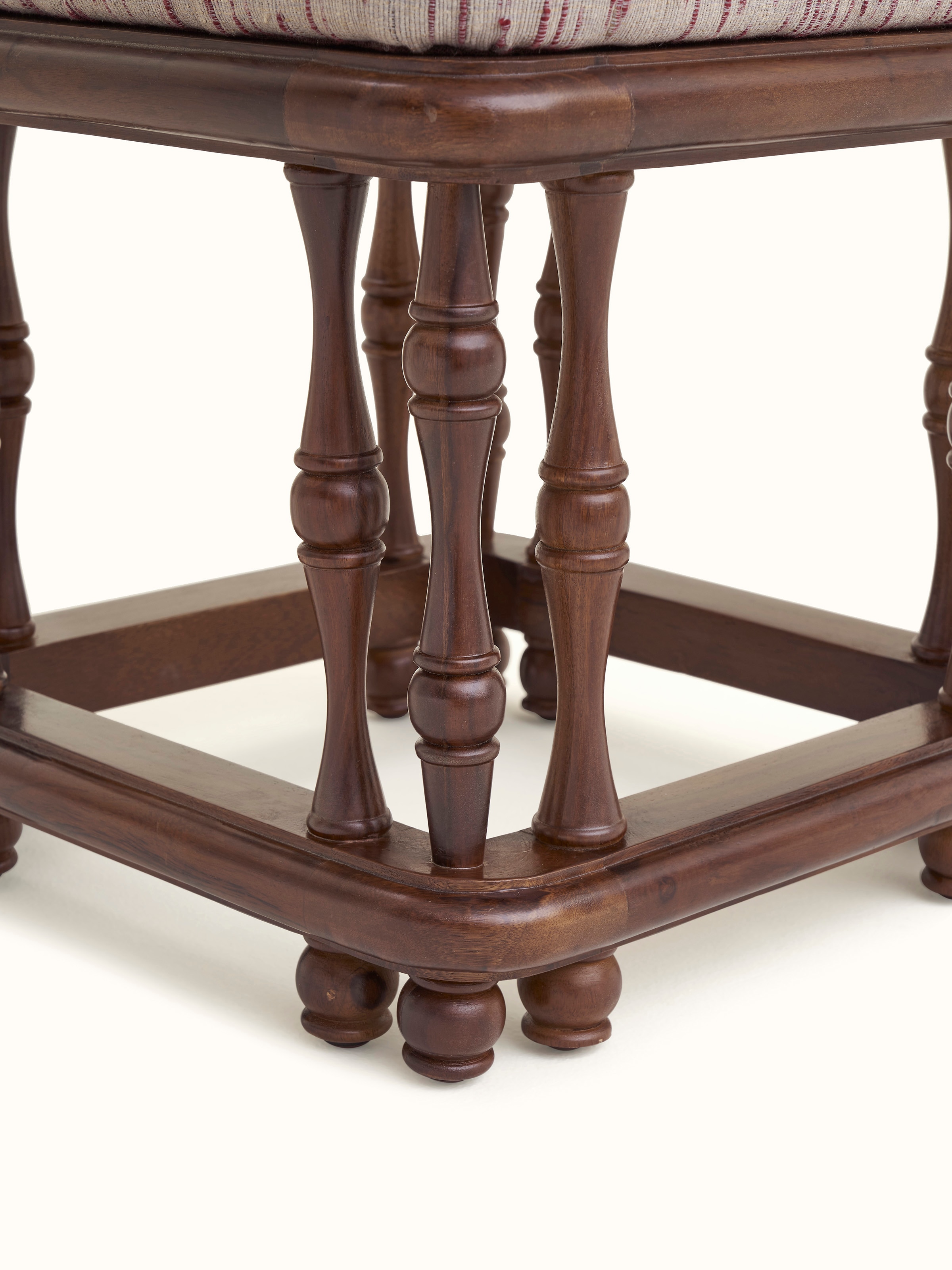 Angled view of the upholstered Sheesham wood ottoman, emphasizing the ottoman's design and upholstered top.