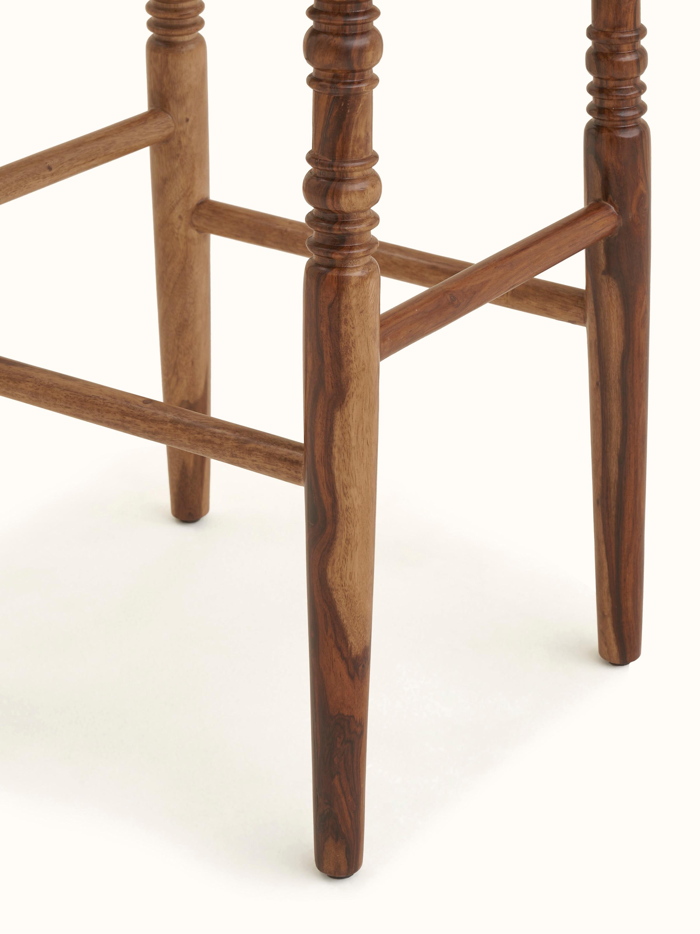 Angled view of the bar stool, emphasizing the round seat and Sheesham wood base with block print details.