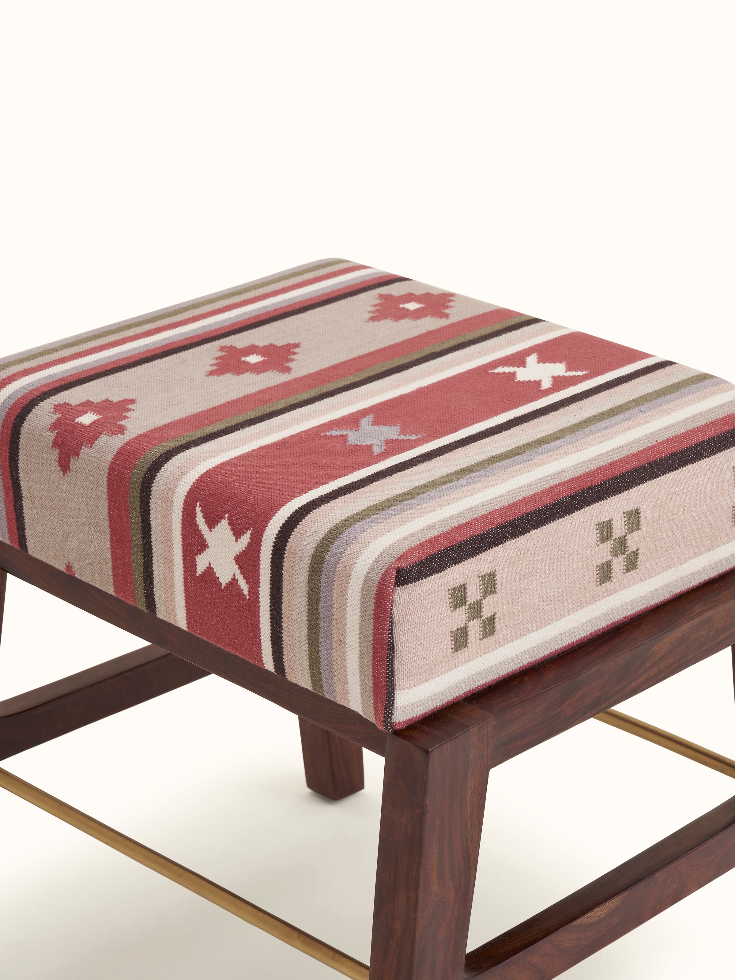 Angled view of the Sheesham wood ottoman with Panja Dhurrie upholstery, showing the integration of the metal connector.