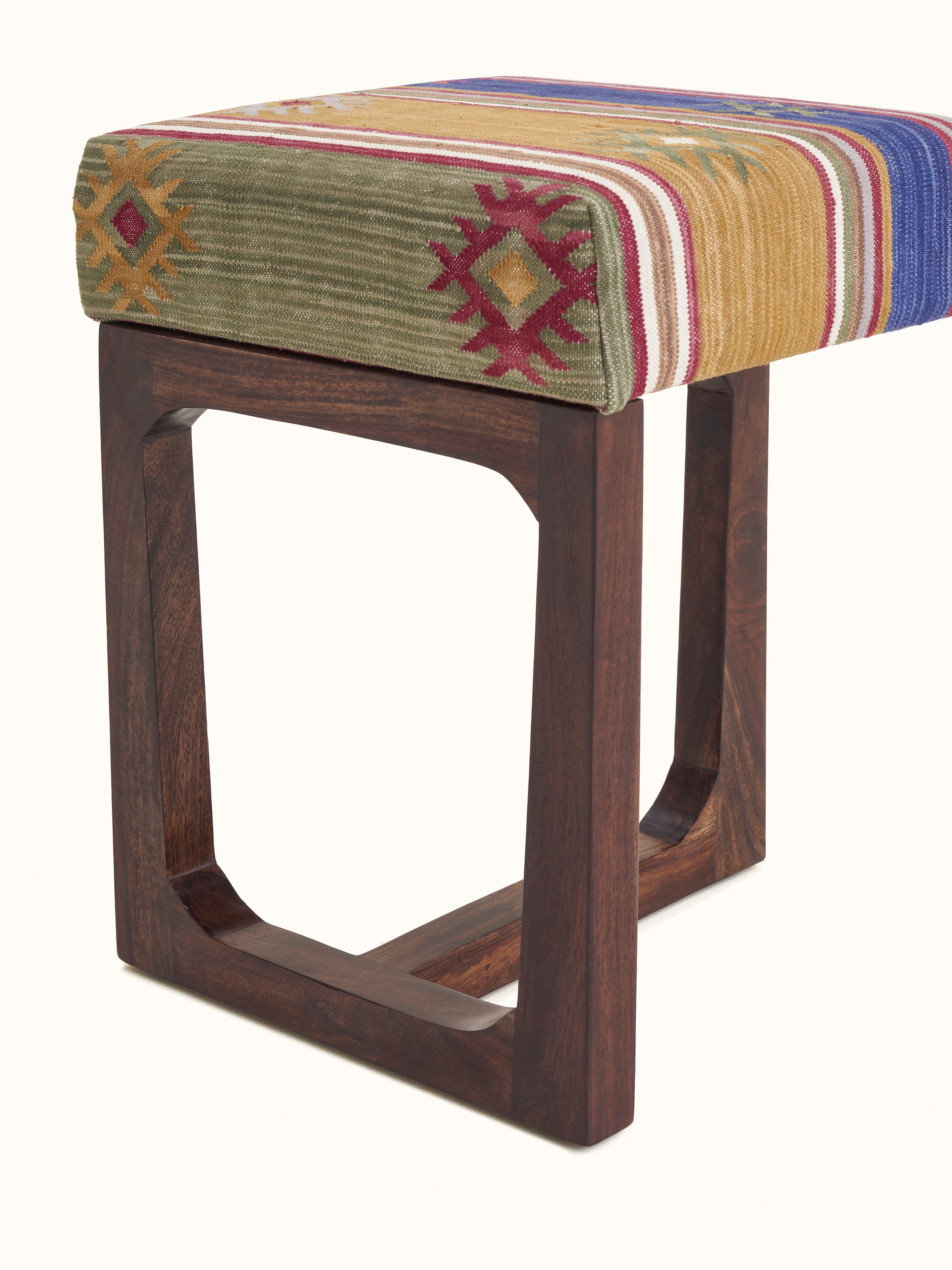 Side view of the Panja Dhurrie stool, emphasizing the combination of upholstered fabric and Sheesham wood legs
