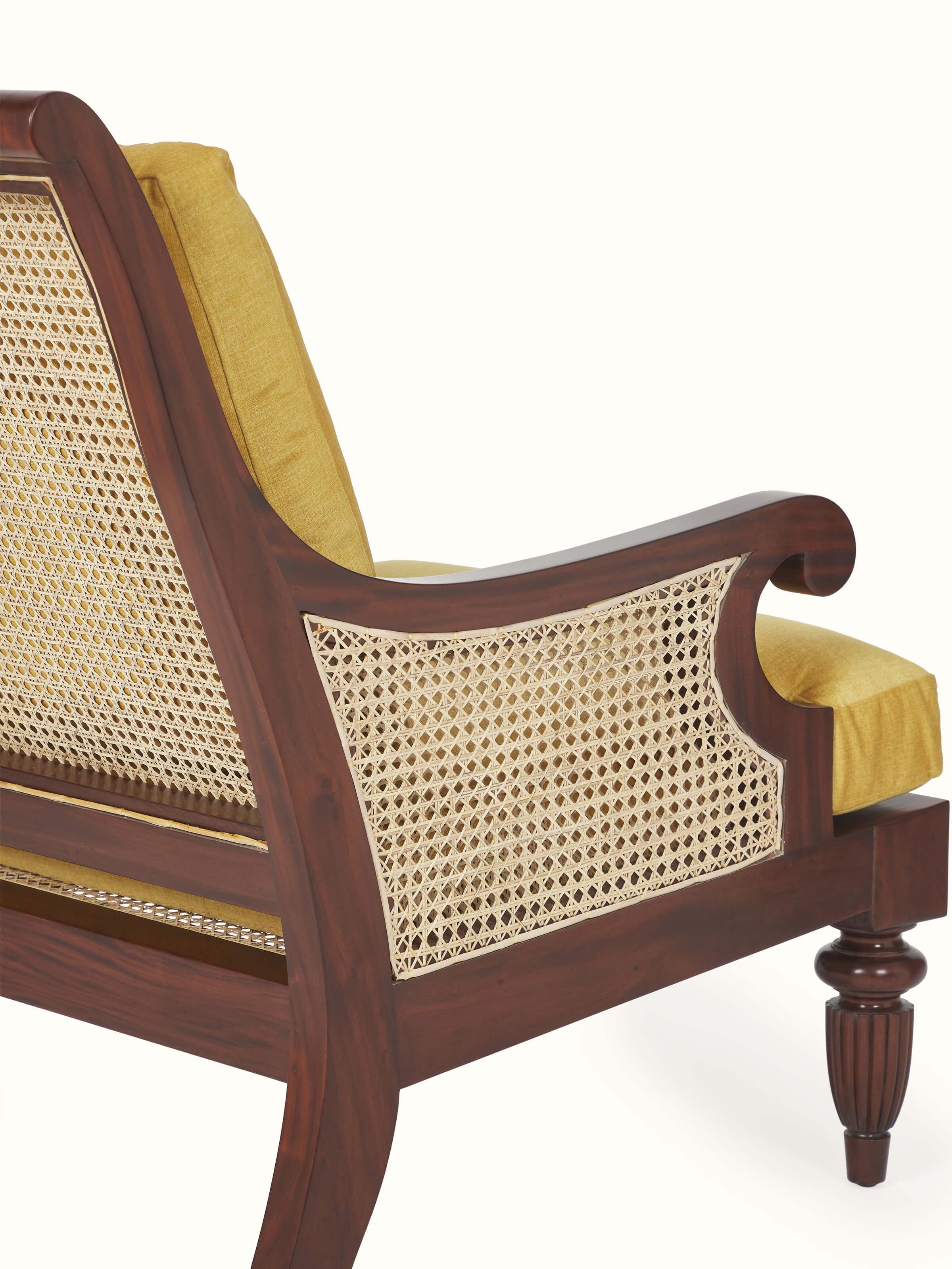 Back view of upholstered mahogany wood & cane armchair, showcasing detailed wood craftsmanship
