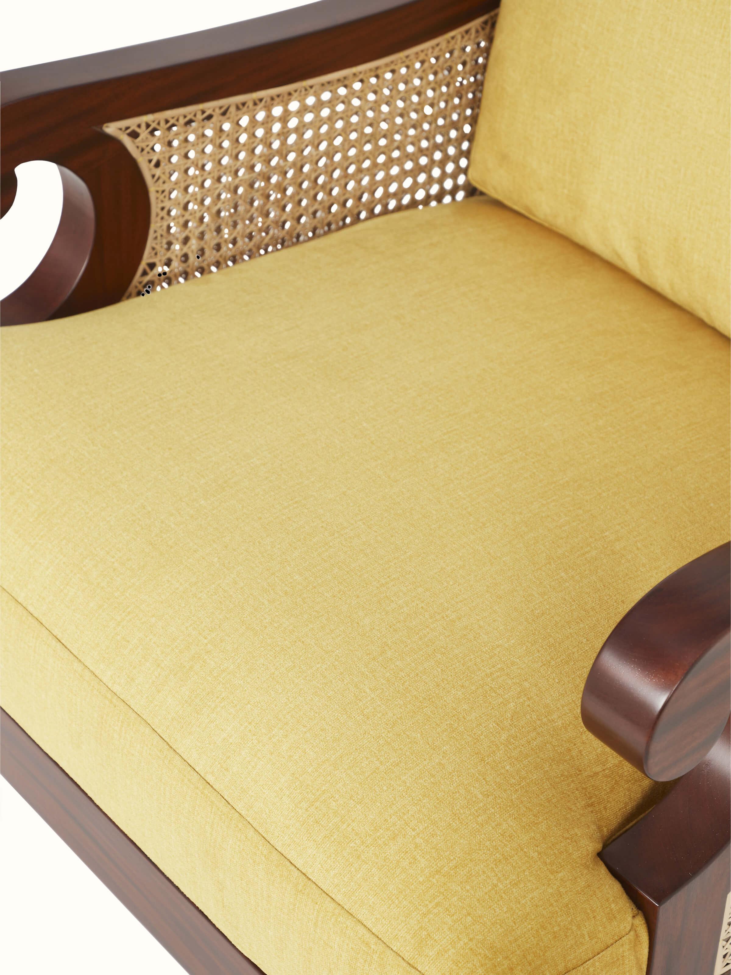Detailed view of armrest on upholstered mahogany wood & cane armchair, highlighting cane work and wood finish