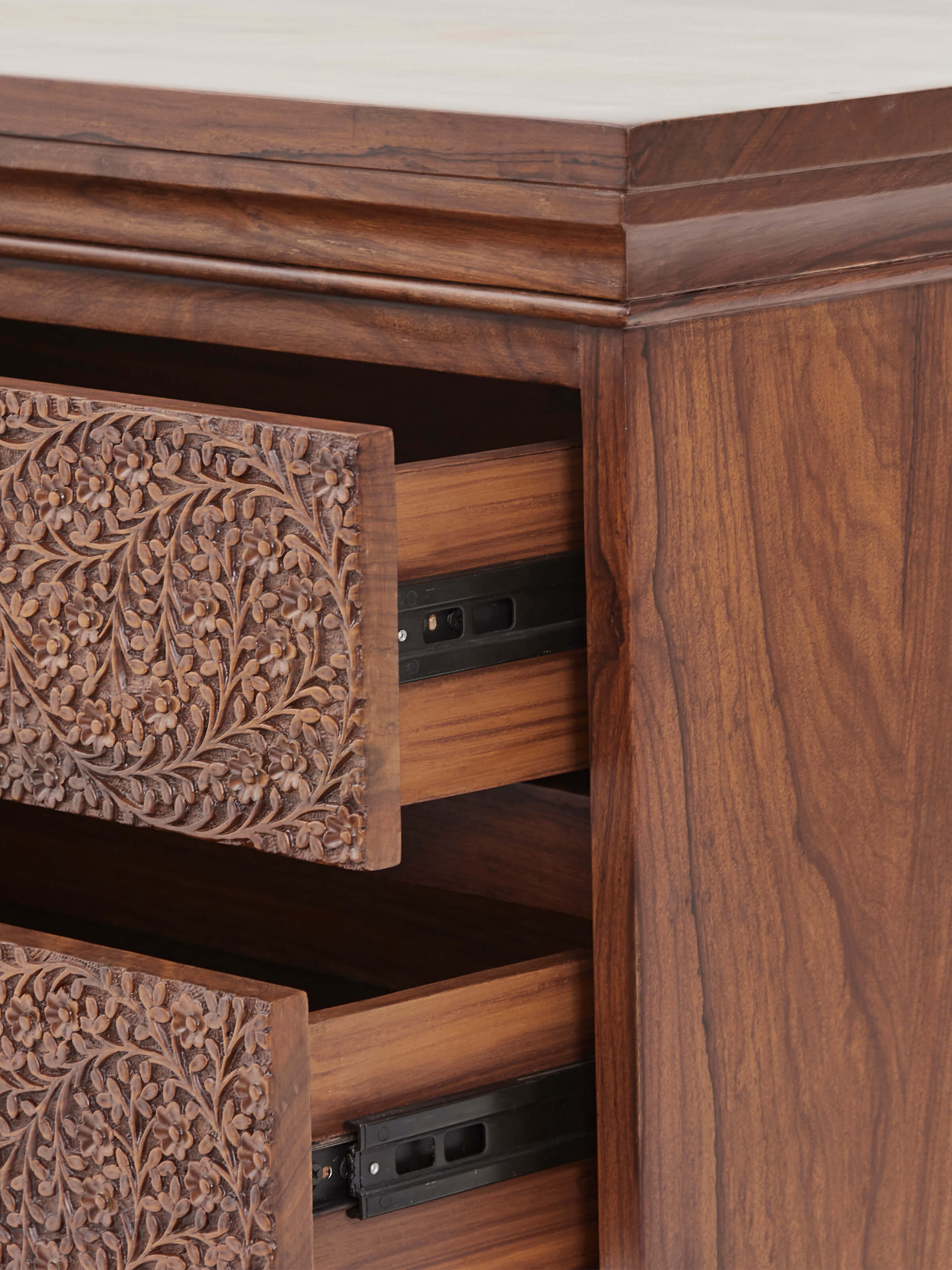 Close-up view of Carved Sheesham Chest of Drawers showcasing intricate drawer designs and wood grain.