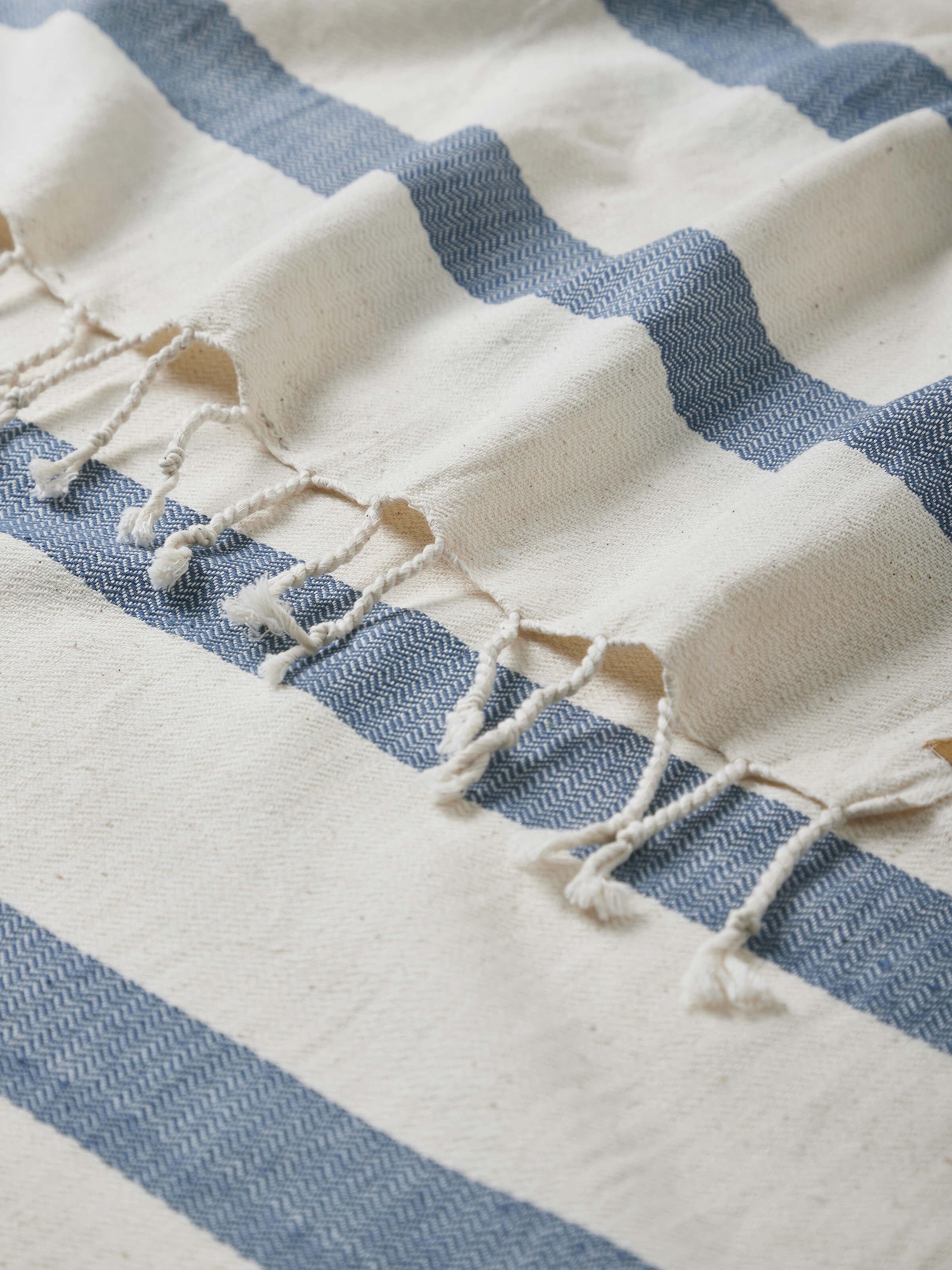 Side view of Salya blue stripe cotton bath towel (M), showing the thickness and drape of the towel.