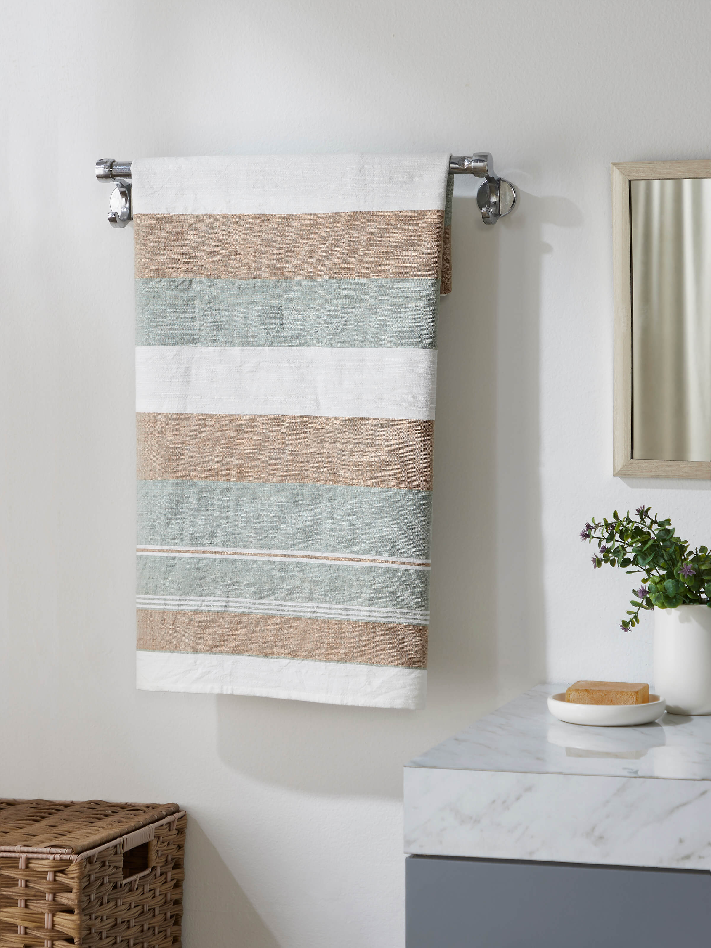 Lifestyle image of a green cotton striped bath towel, displayed in a modern bathroom setting.