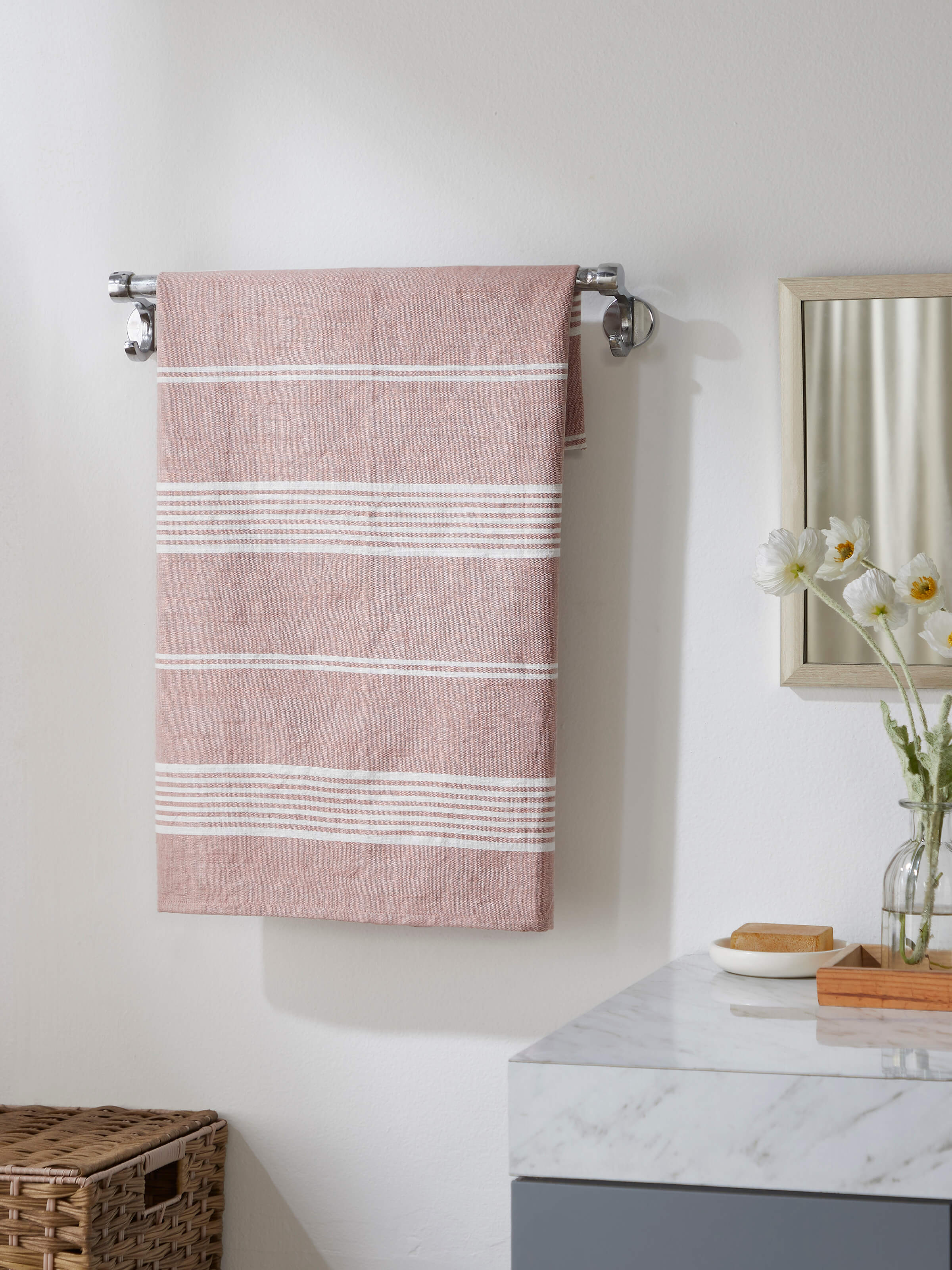 Lifestyle shot of Simhi Pink Stripe Cotton Bath Towel (L) hanging on a rack, displaying its elegant pink stripes.