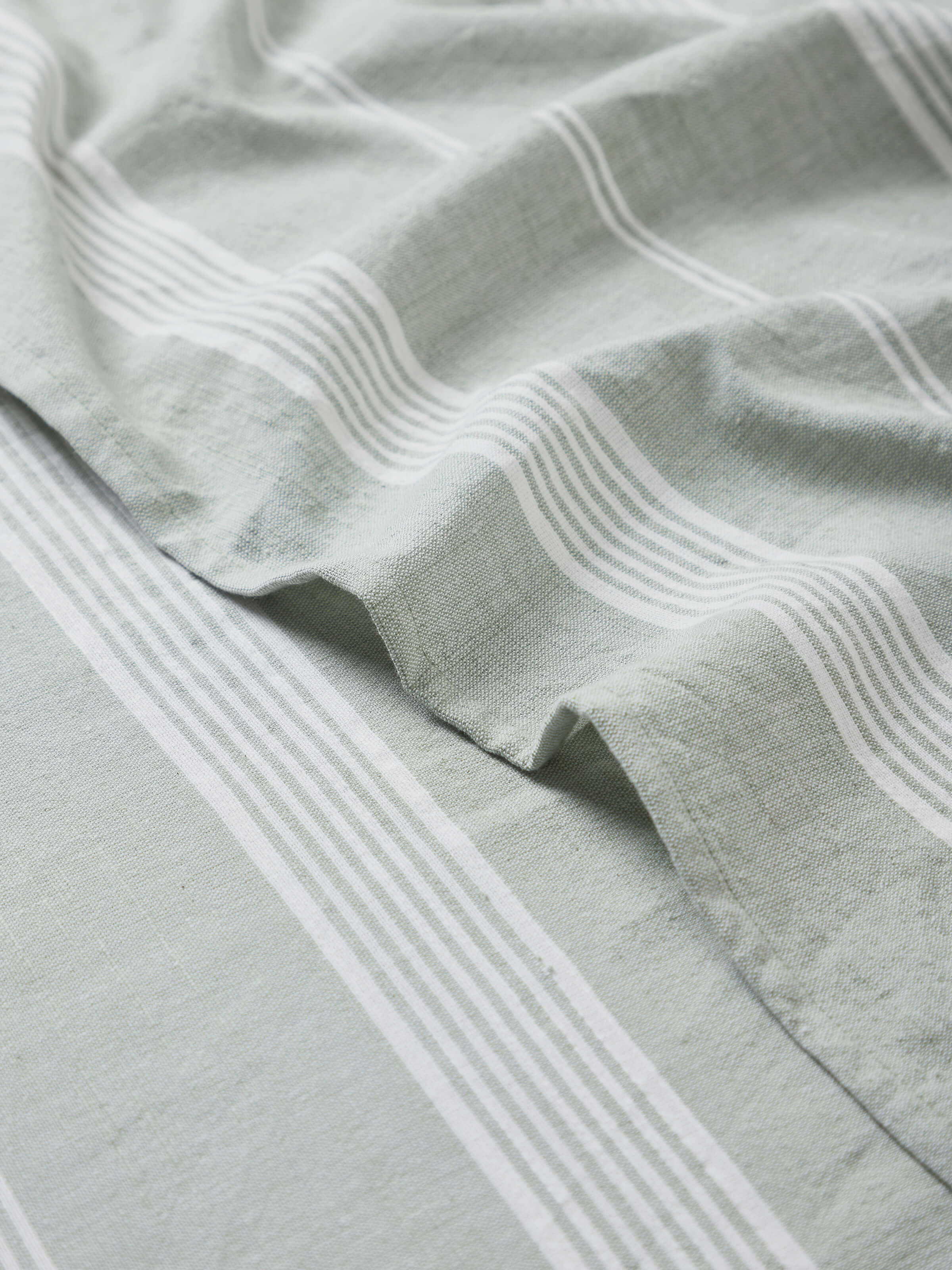 Angle view of Simhi Green Stripe Cotton Bath Towel (M) focusing on the towel's drape and stripe pattern.