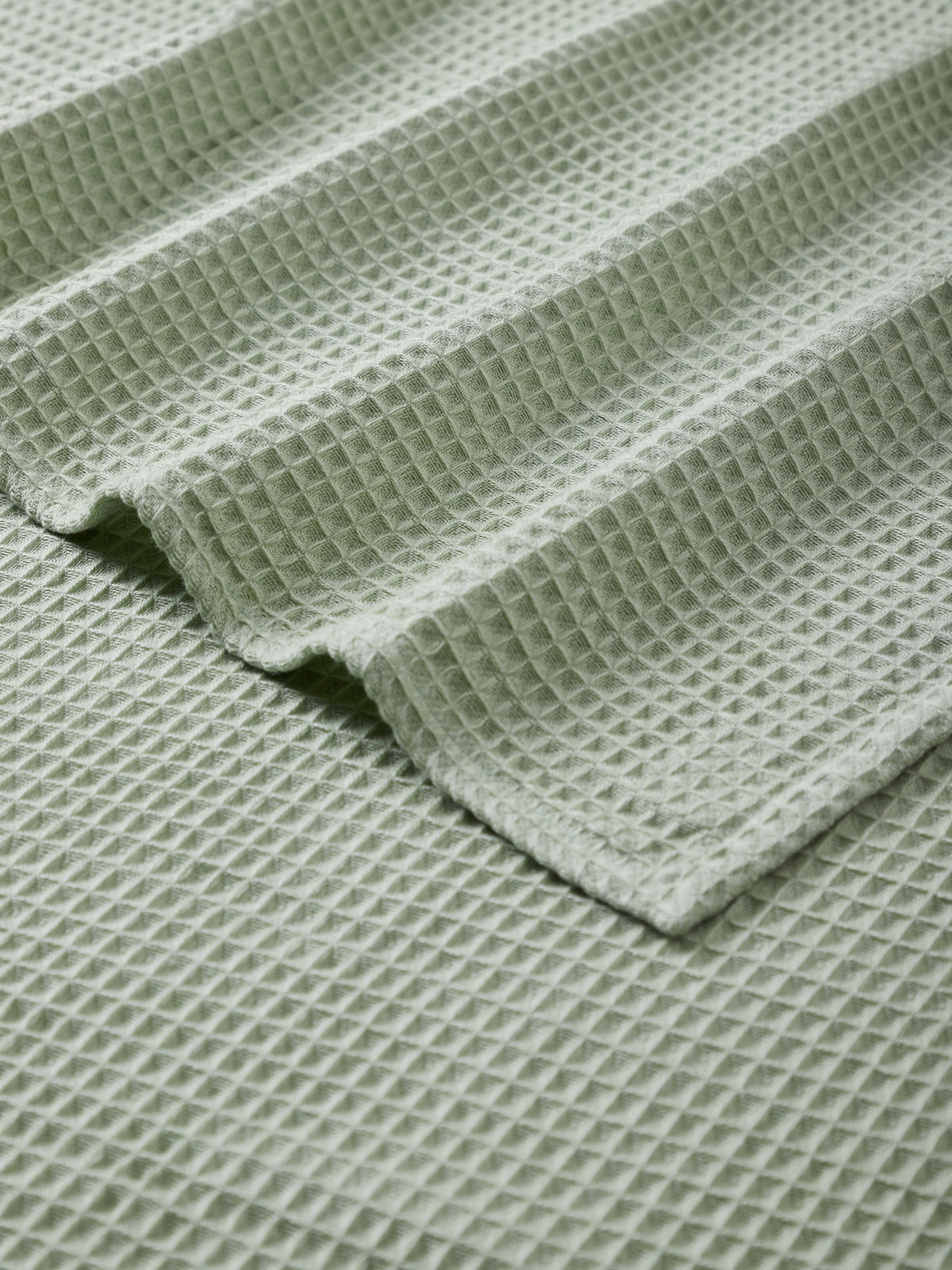 Side view of Amala waffle green solid cotton bath towel (M), highlighting the thickness and plushness of the towel.