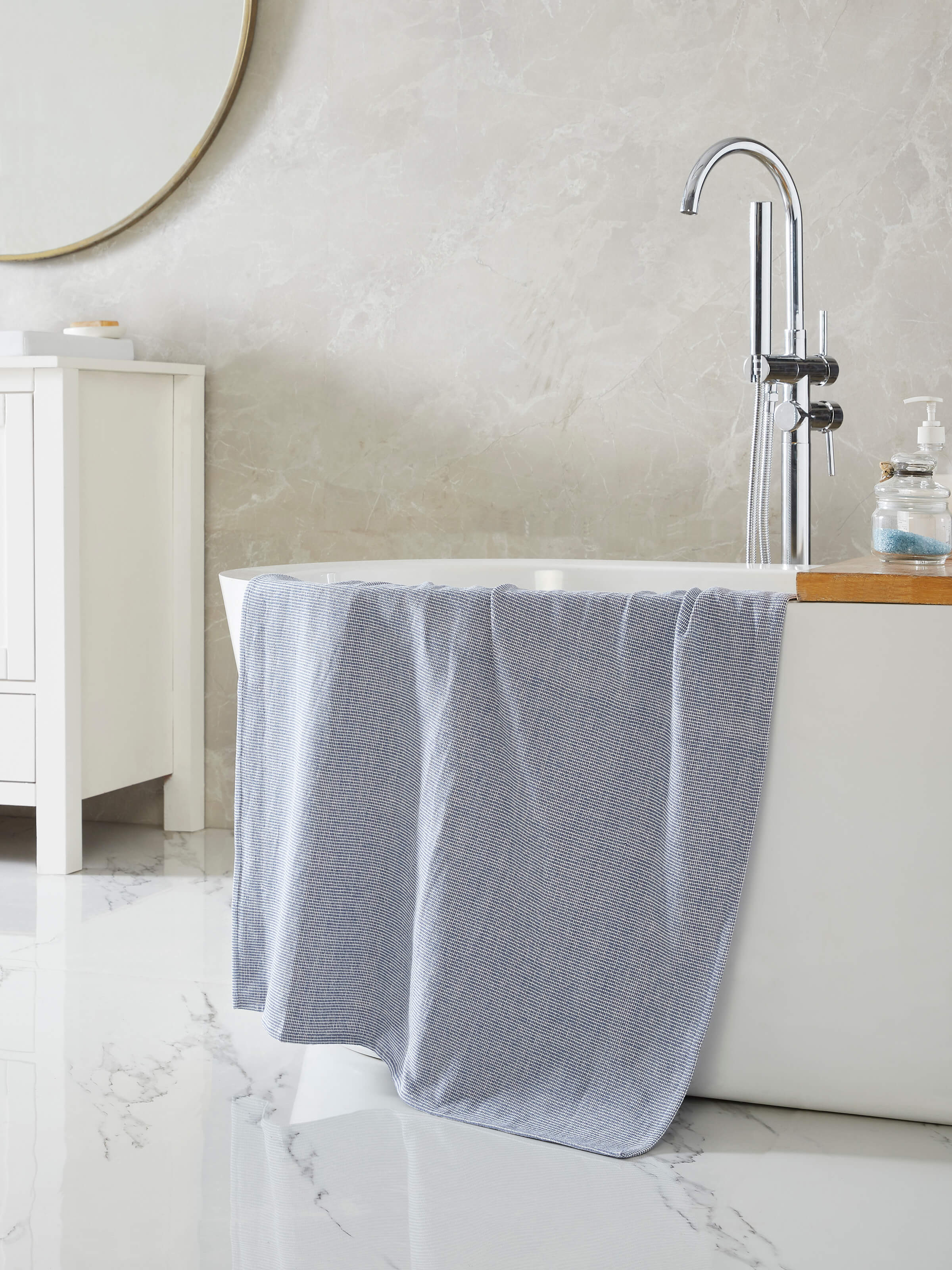 Lifestyle image of Shikara Blue Chambray Cotton Bath Towel (M) hanging in a bathroom setting.