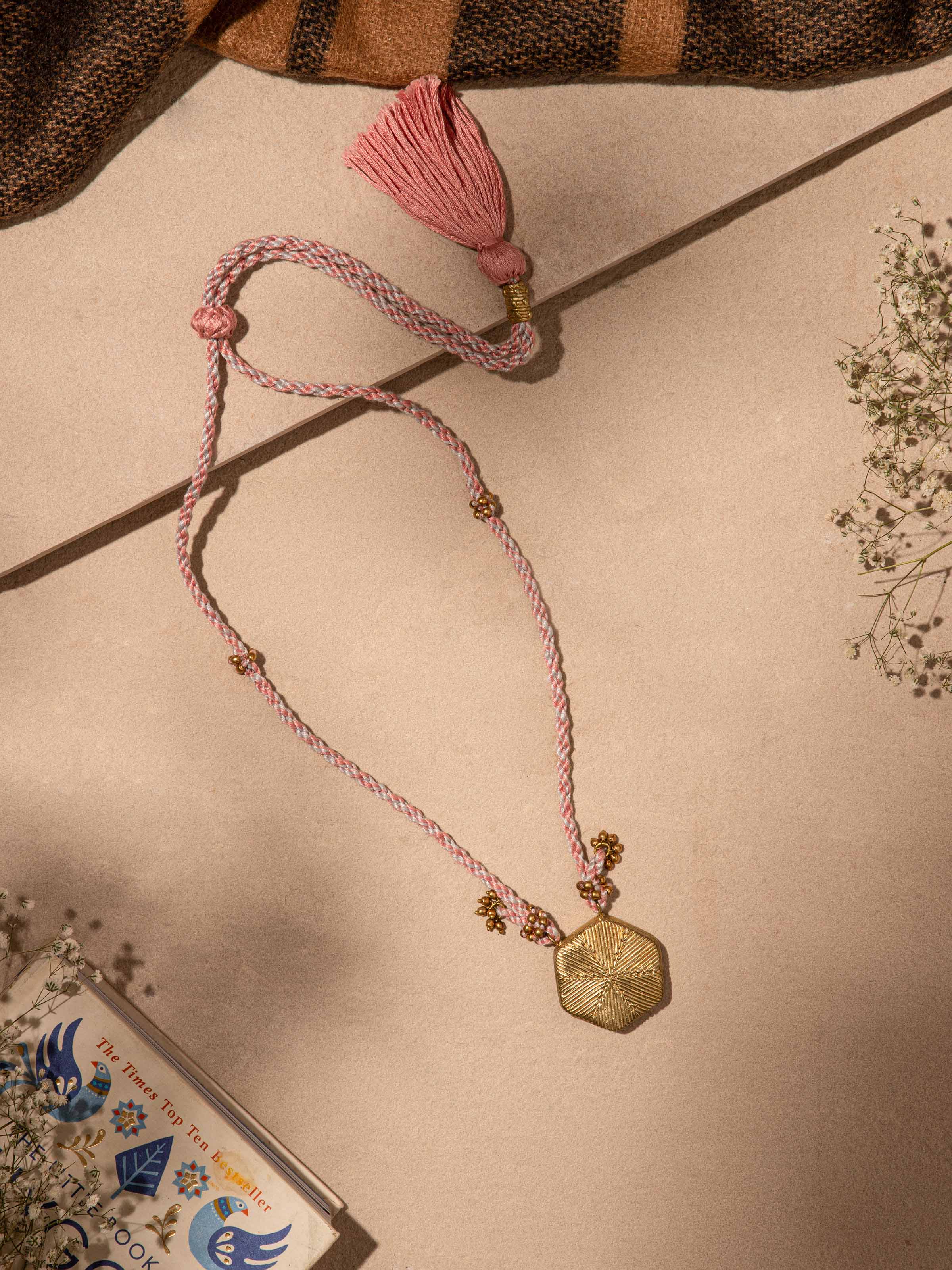 Close-up of Dhokra pendant and chain showing detailed metalwork and traditional motifs.