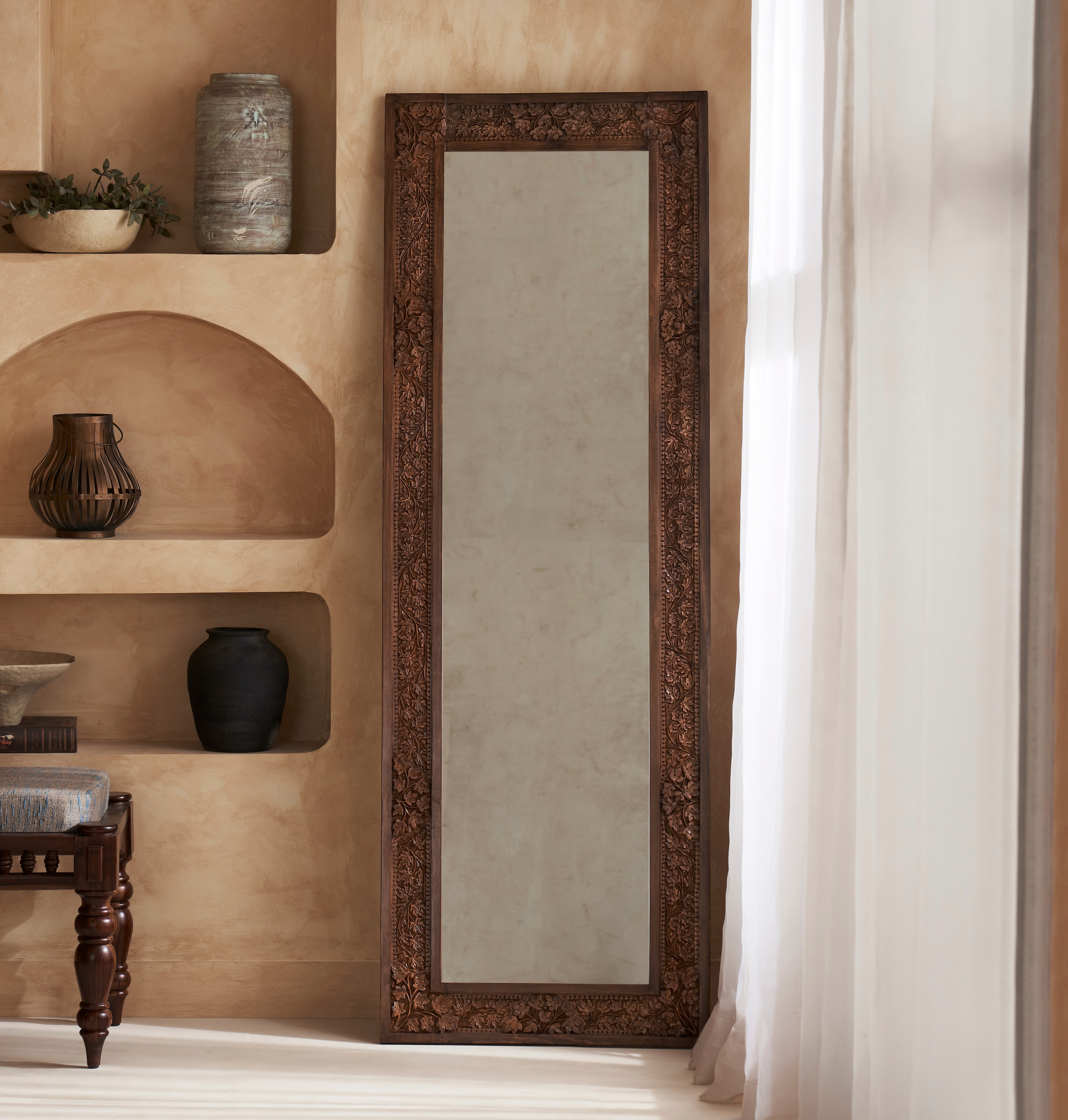 Side view of the walnut wood and glass full-length mirror, showcasing the detailed carving and frame.