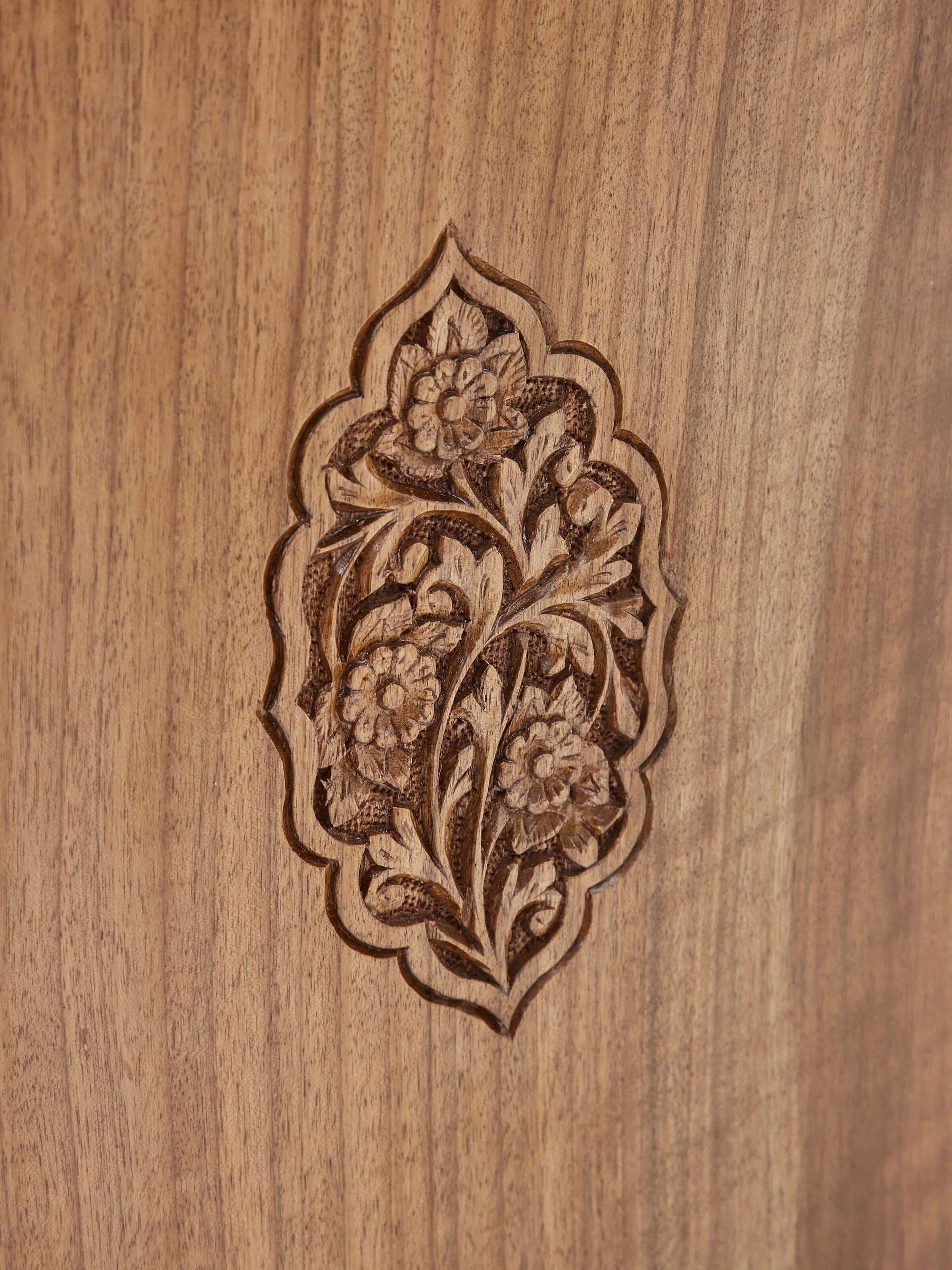Detailed view of the carving on the walnut wood bedside table, focusing on the craftsmanship and design