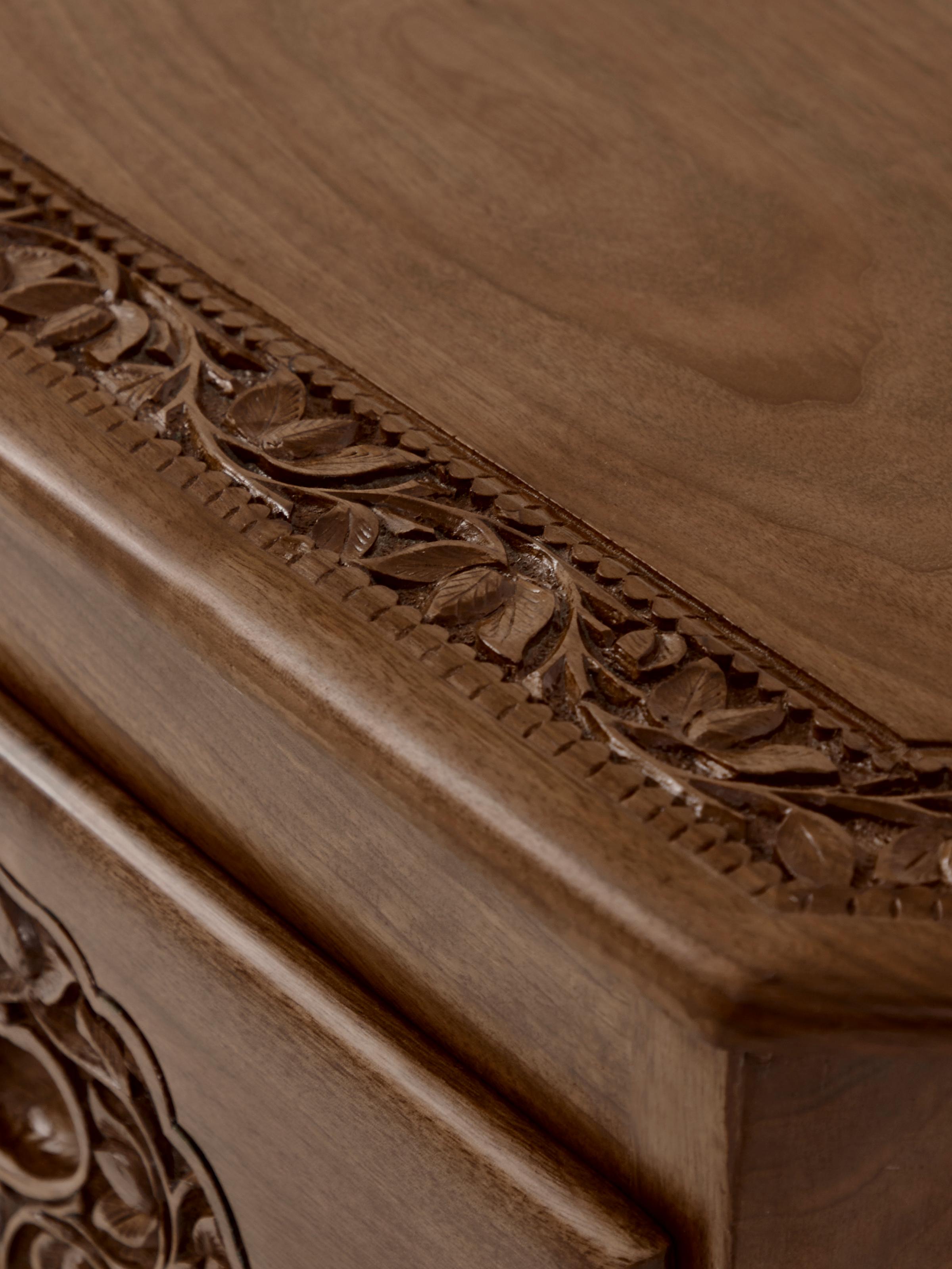 Detailed view of the sideboard's carved surface and drawer handles, showcasing the fine craftsmanship