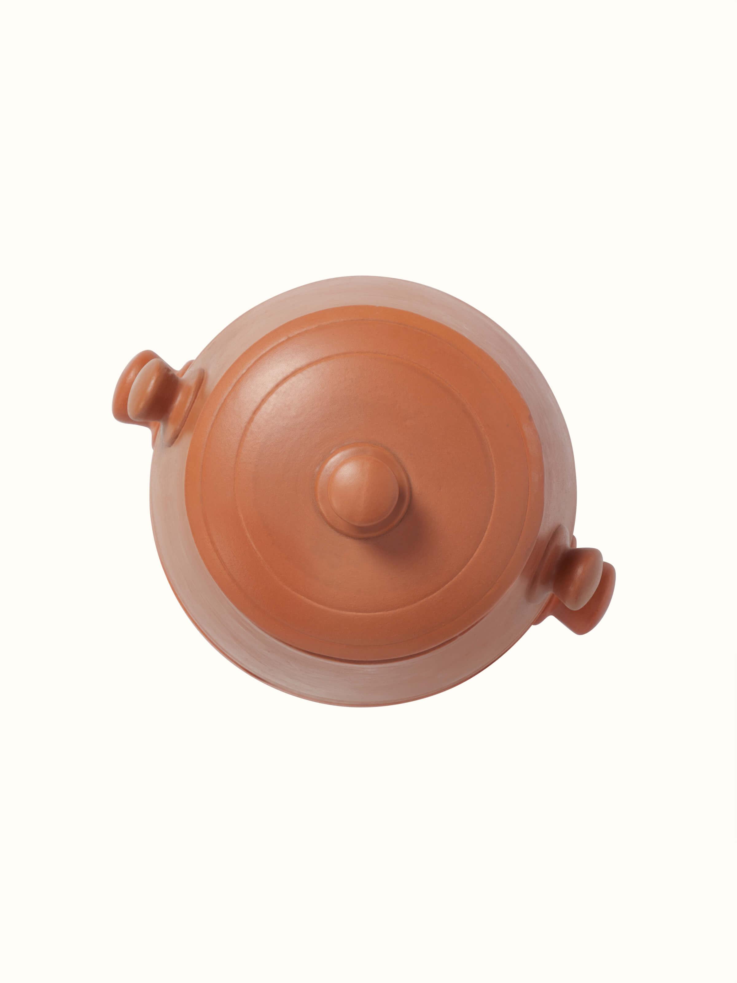 Close-up view of tall terracotta clay cooking pot emphasizing its robust texture.