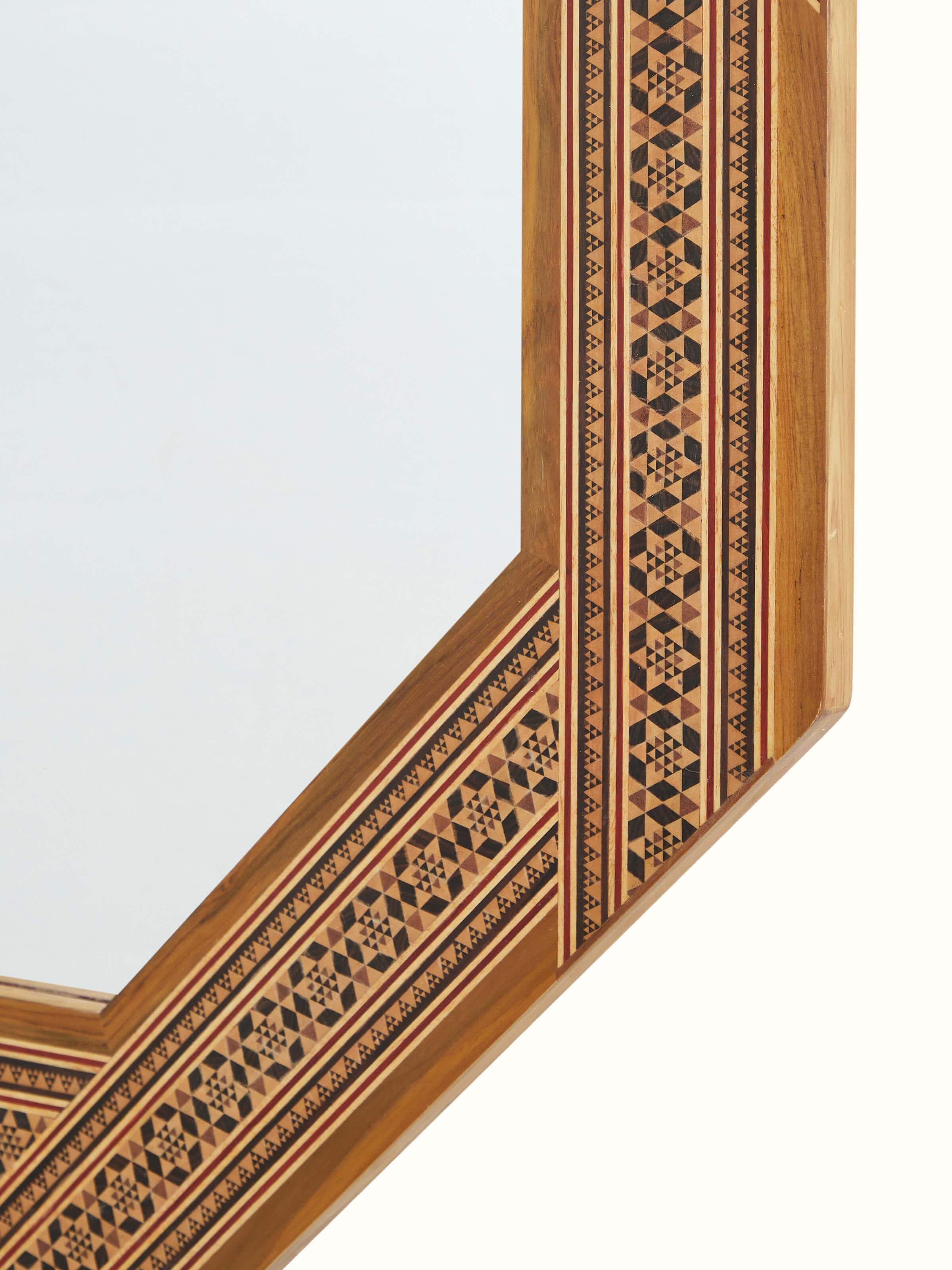 Angle view of the teak wood marquetry octagonal wall mirror, showing the mirror frame's geometric design and finish.