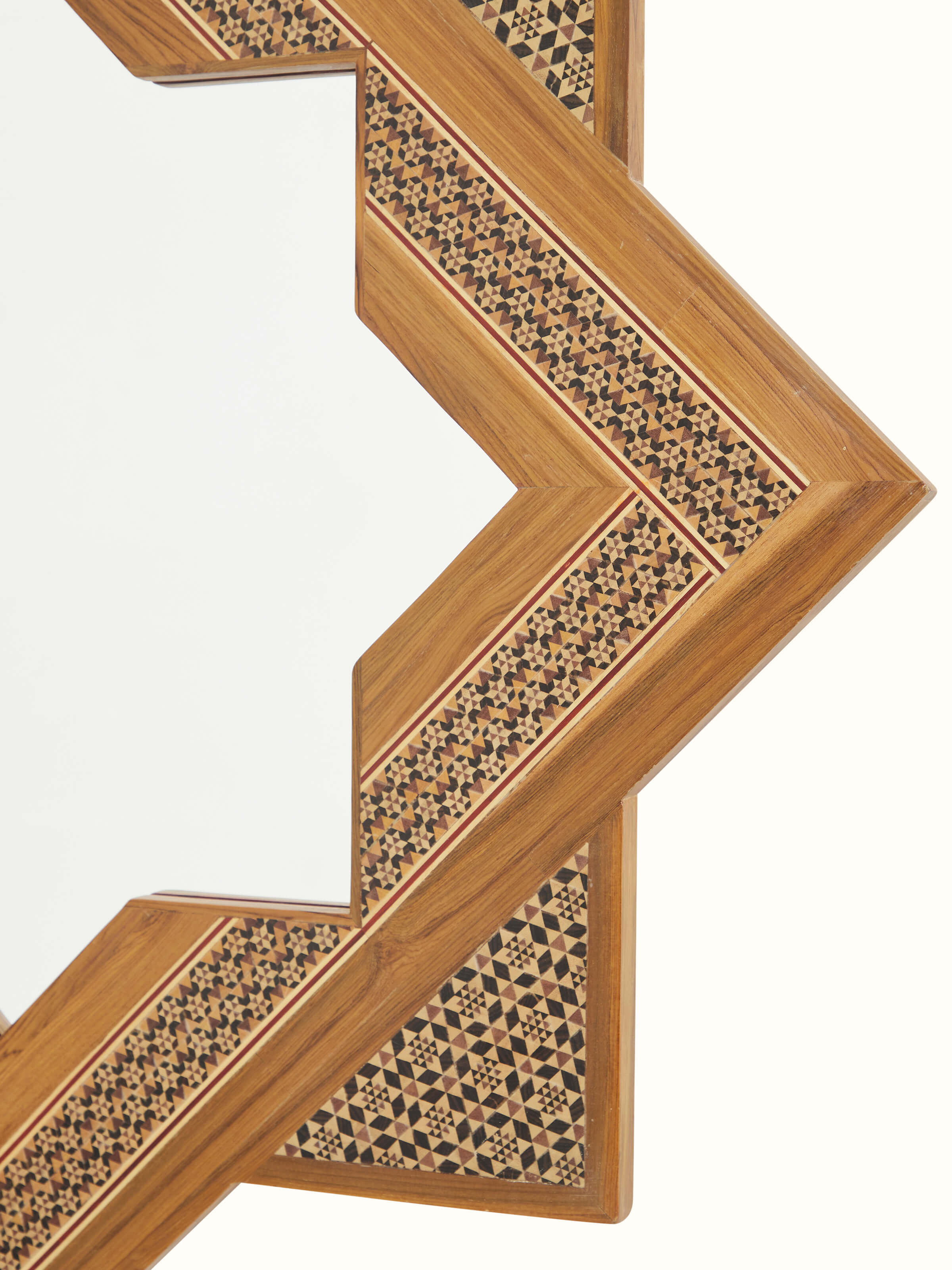 Detailed view of the star-shaped teak wood marquetry wall mirror from a different angle, showcasing the reflective surface and edges.
