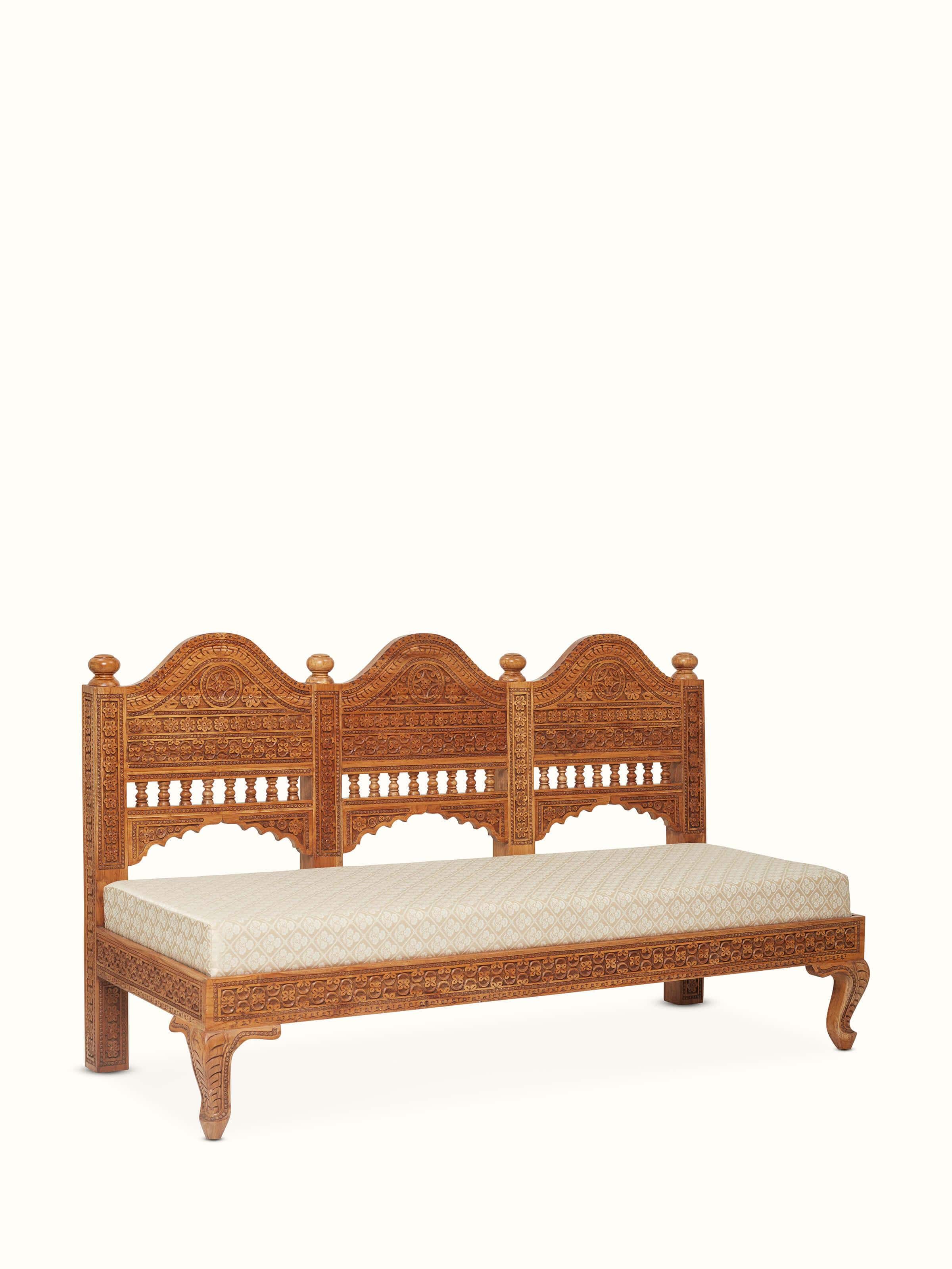 Angled view of the upholstered Sheesham wood sofa, highlighting detailed carvings and elegant design