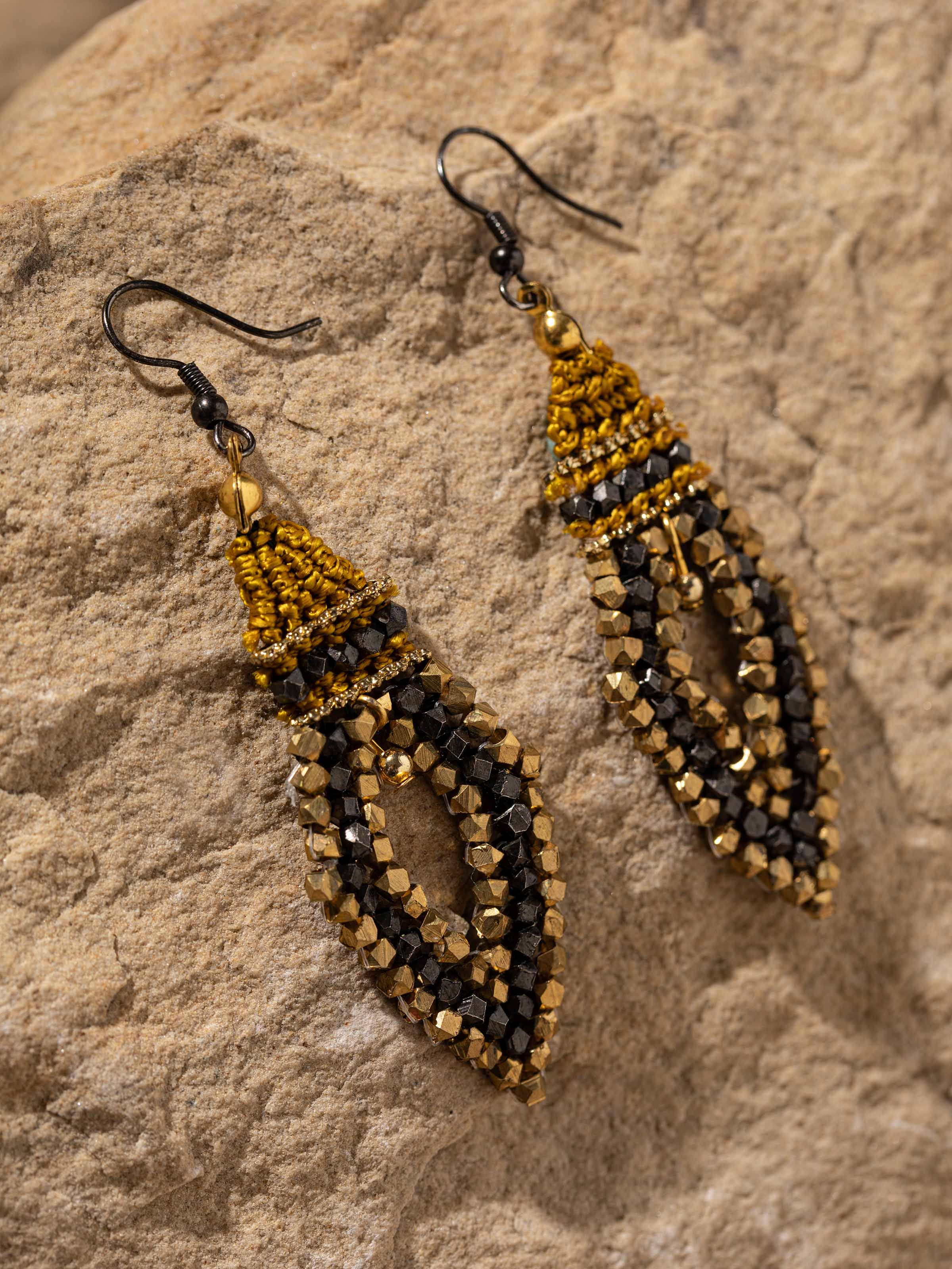 Detailed close-up of handcrafted drop earrings focusing on the texture and design elements.