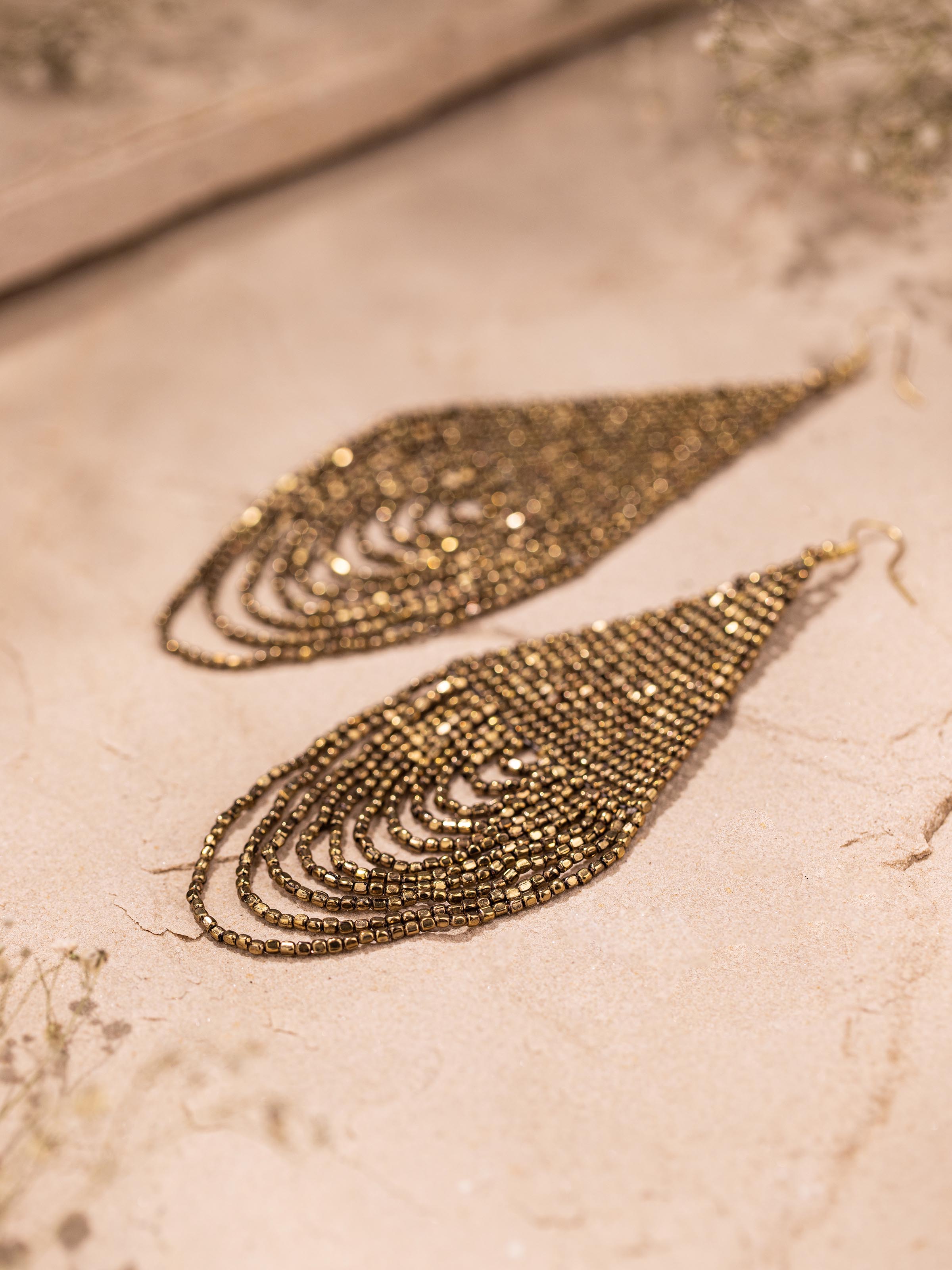 Detailed close-up of handcrafted drop earrings focusing on the earring hooks and design elements.