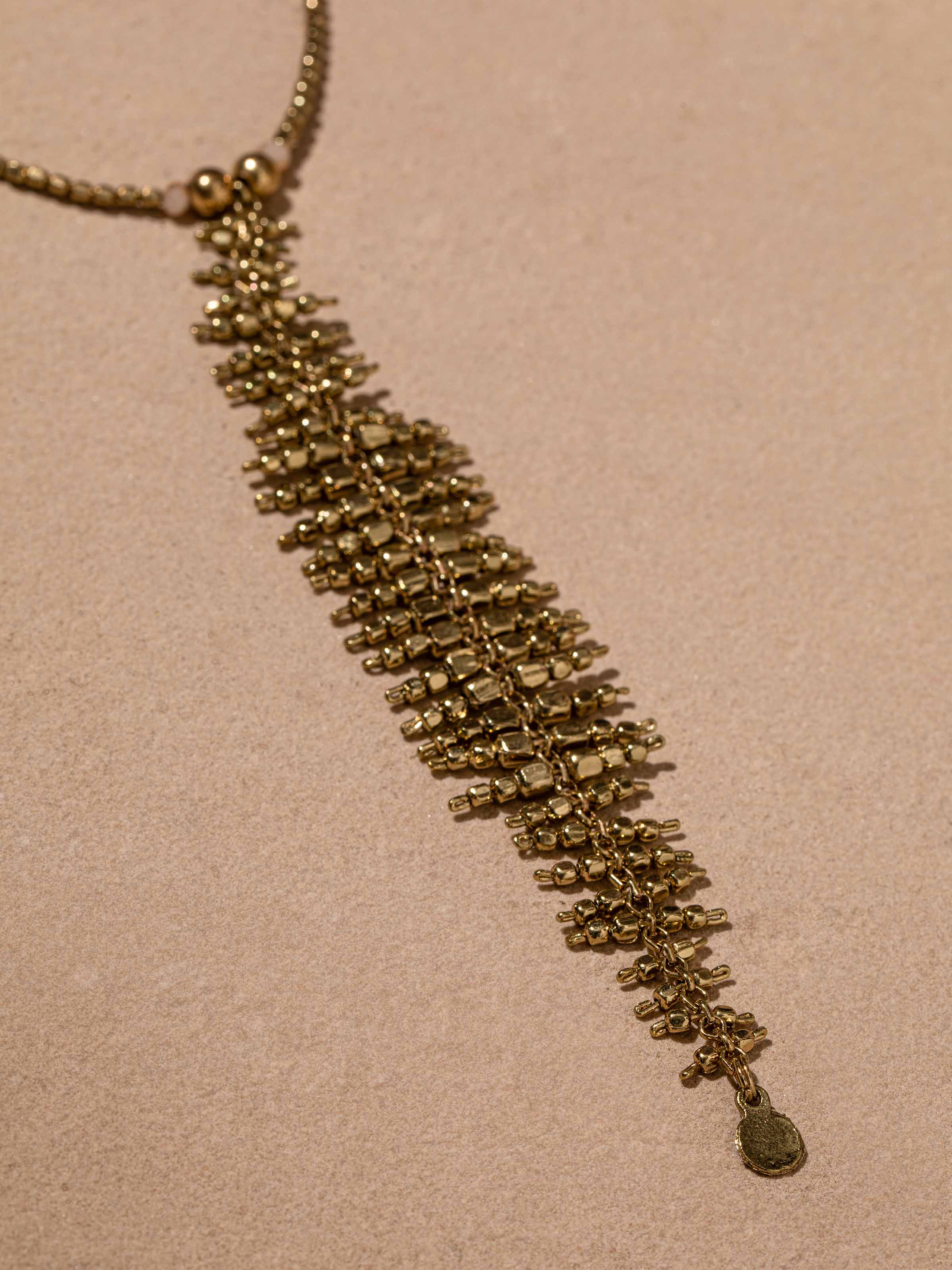Detailed view of handcrafted long necklace with attention to beadwork and artistic embellishments