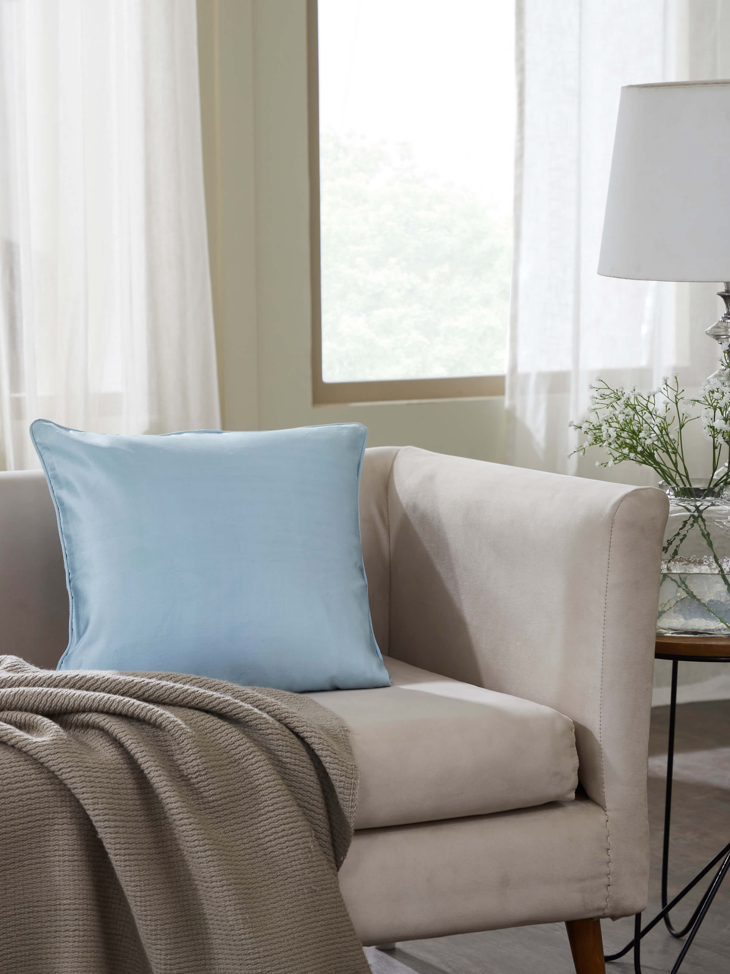 Lifestyle view of Banarasi silk satin cushion cover in light aqua styled on contemporary wooden seating