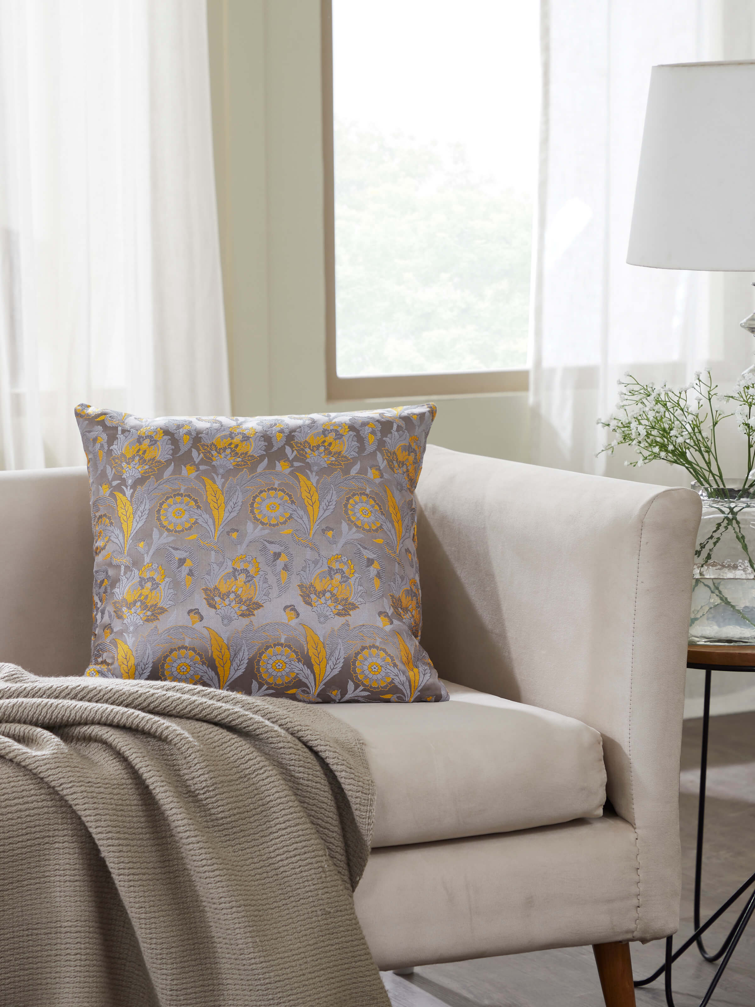 Lifestyle image of grey silk Banarasi cushion cover on a sofa setup