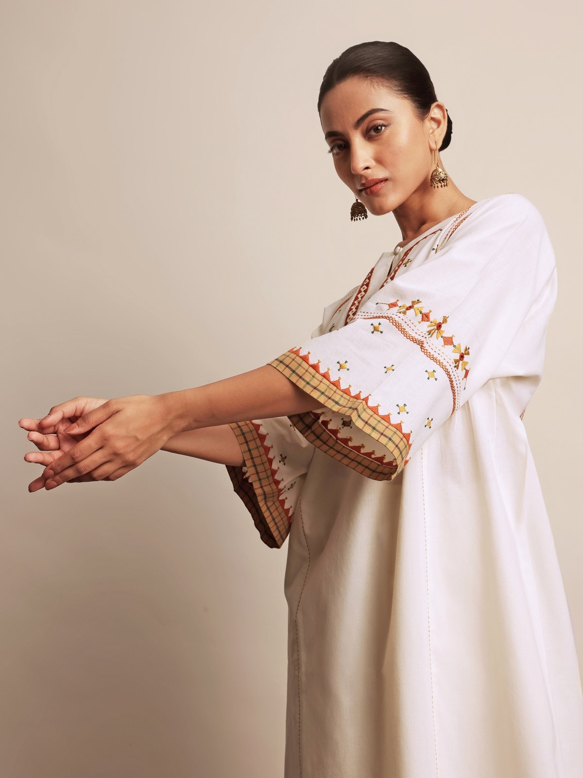 Angled side view of off-white cotton kurta showing detailed embroidery and fabric texture.