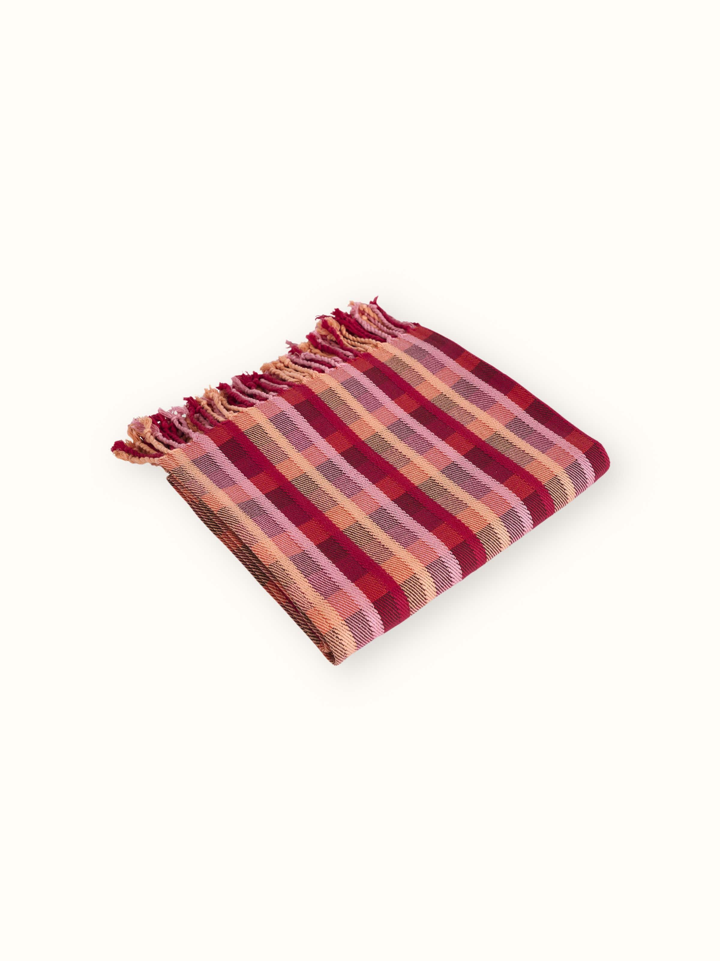 Angled view of Niketa Raspberry Handloom Throw, emphasizing the fabric drape and check pattern detail.