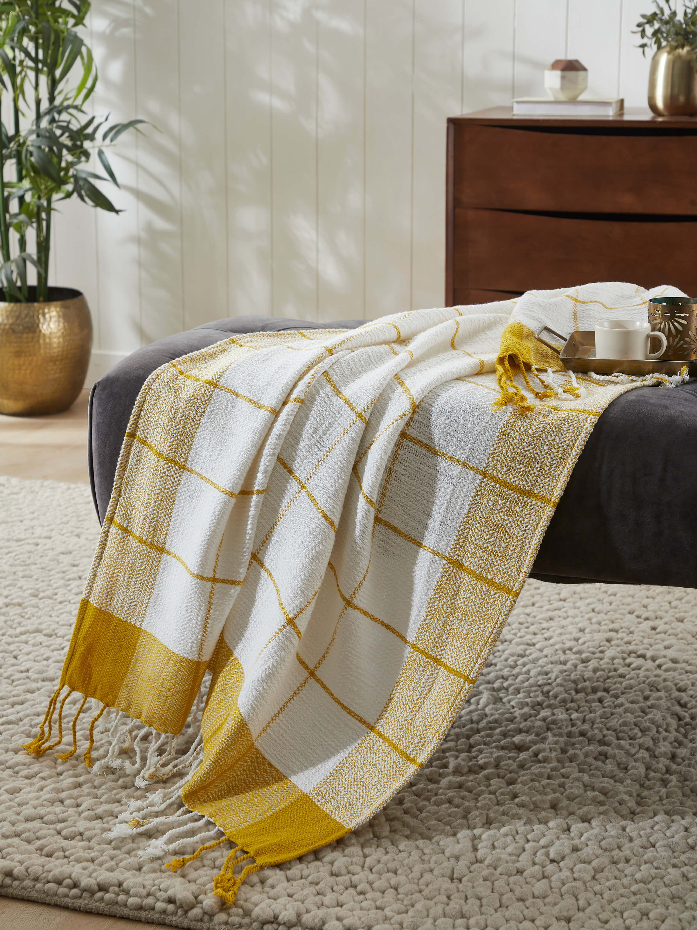 Lifestyle view of Adhima Ochre Cotton Throw draped over a sofa, adding warmth and texture to home decor.