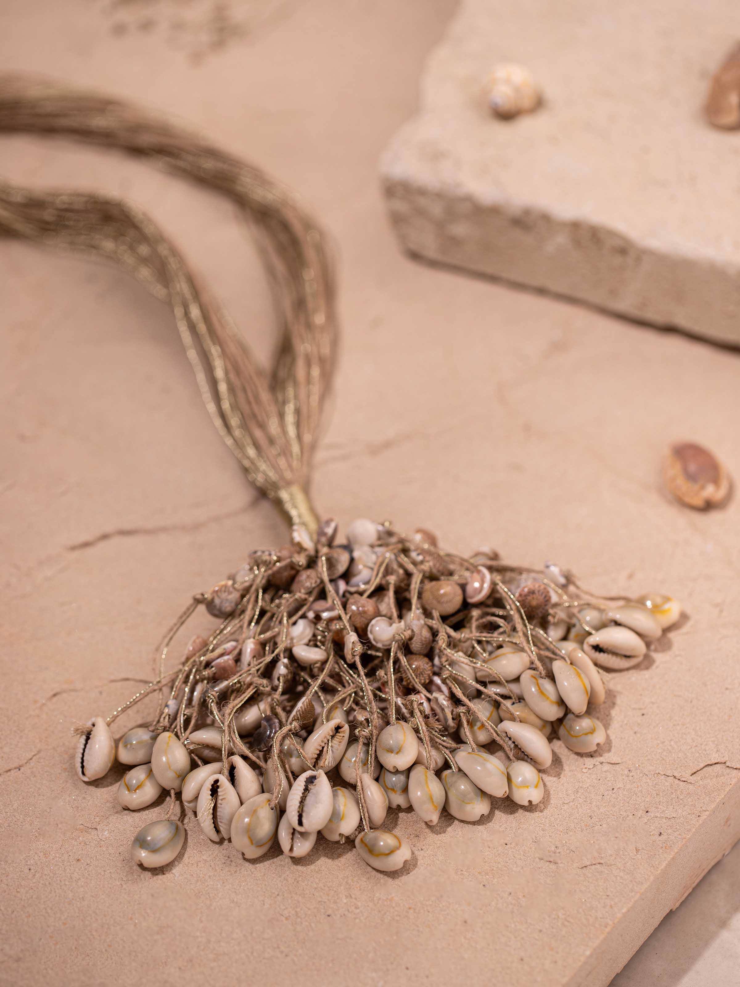 "Detailed view of cowrie shell long necklace focusing on shell and thread design"