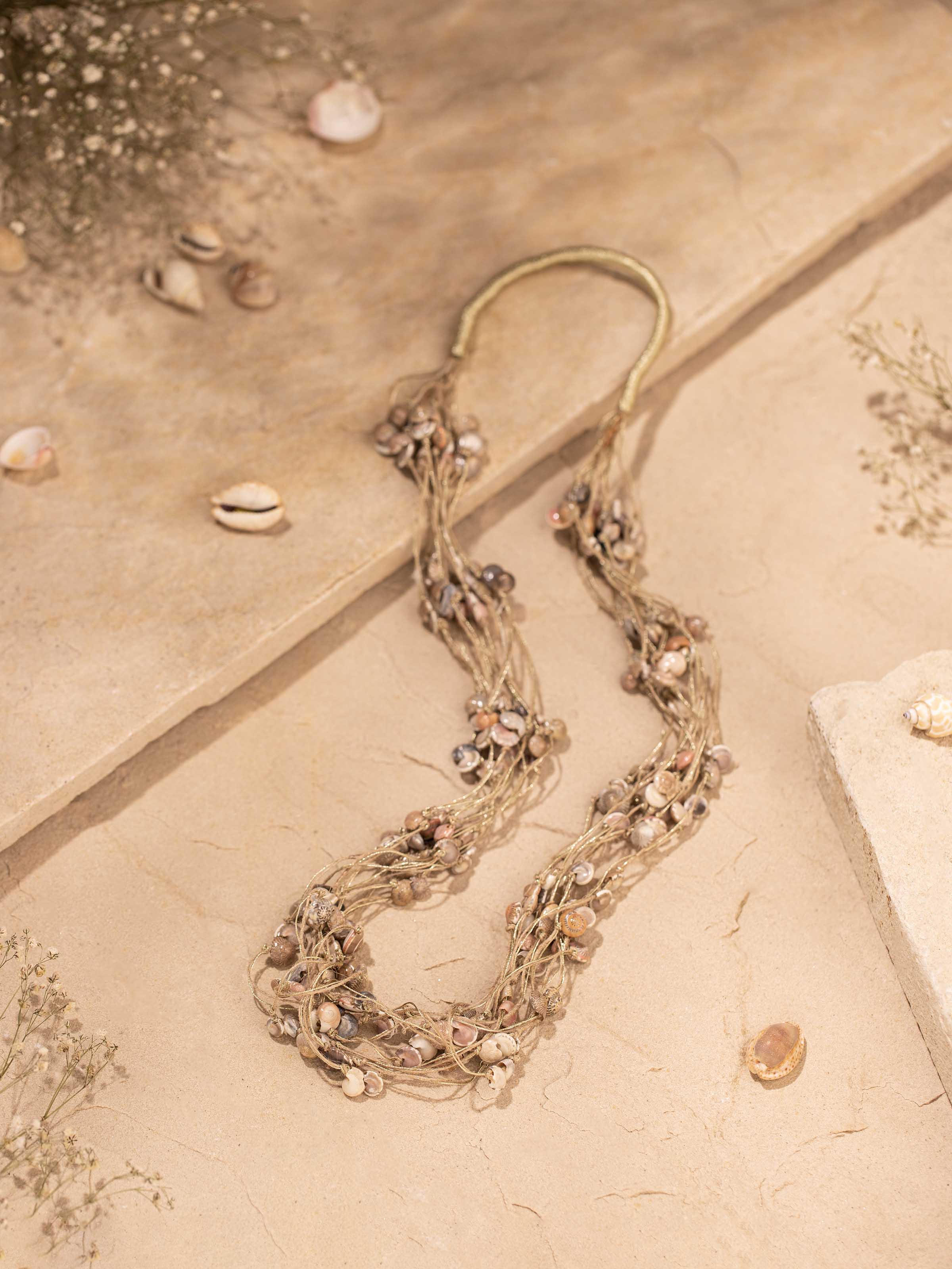 Close-up of cowrie shell long necklace focusing on the detailed shell elements and natural texture.