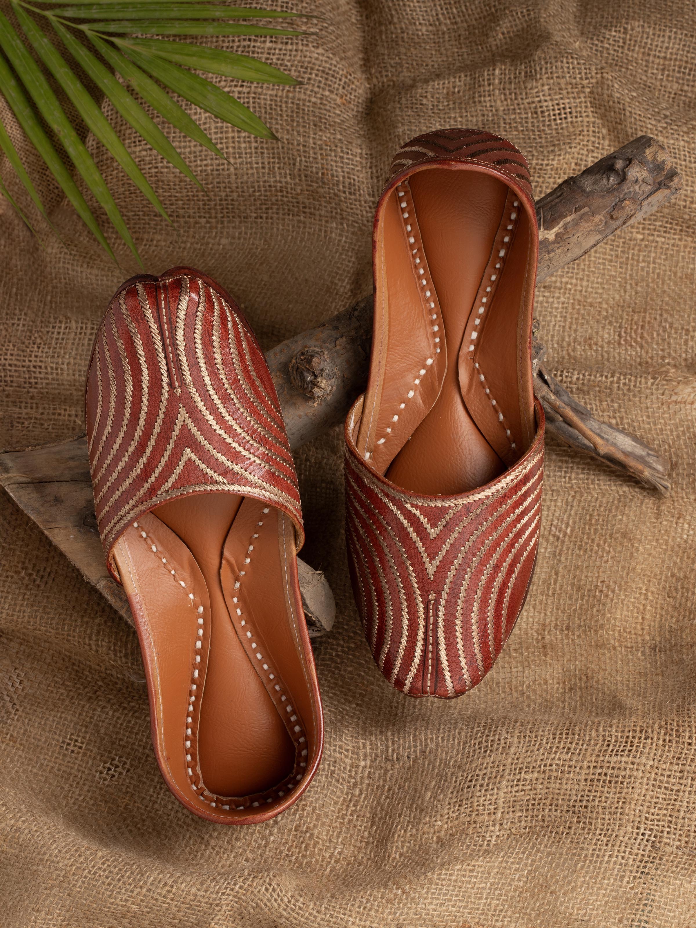 Side view of brown leather embroidered punjabi juttis highlighting detailed craftsmanship